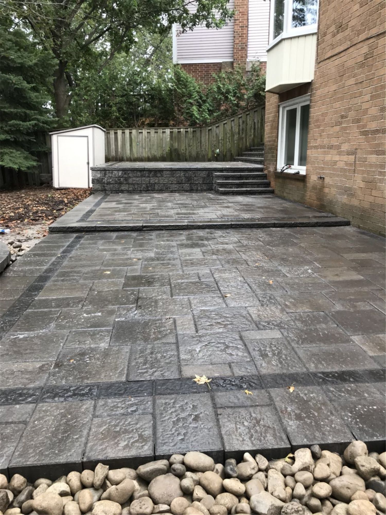 Toronto landscaping renovation featuring a spacious backyard interlock patio designed for outdoor living and entertaining. The durable paving stones, clean edges, and elevated step design create a modern and low-maintenance outdoor space that enhances both functionality and landscape aesthetics for a Toronto residential property.