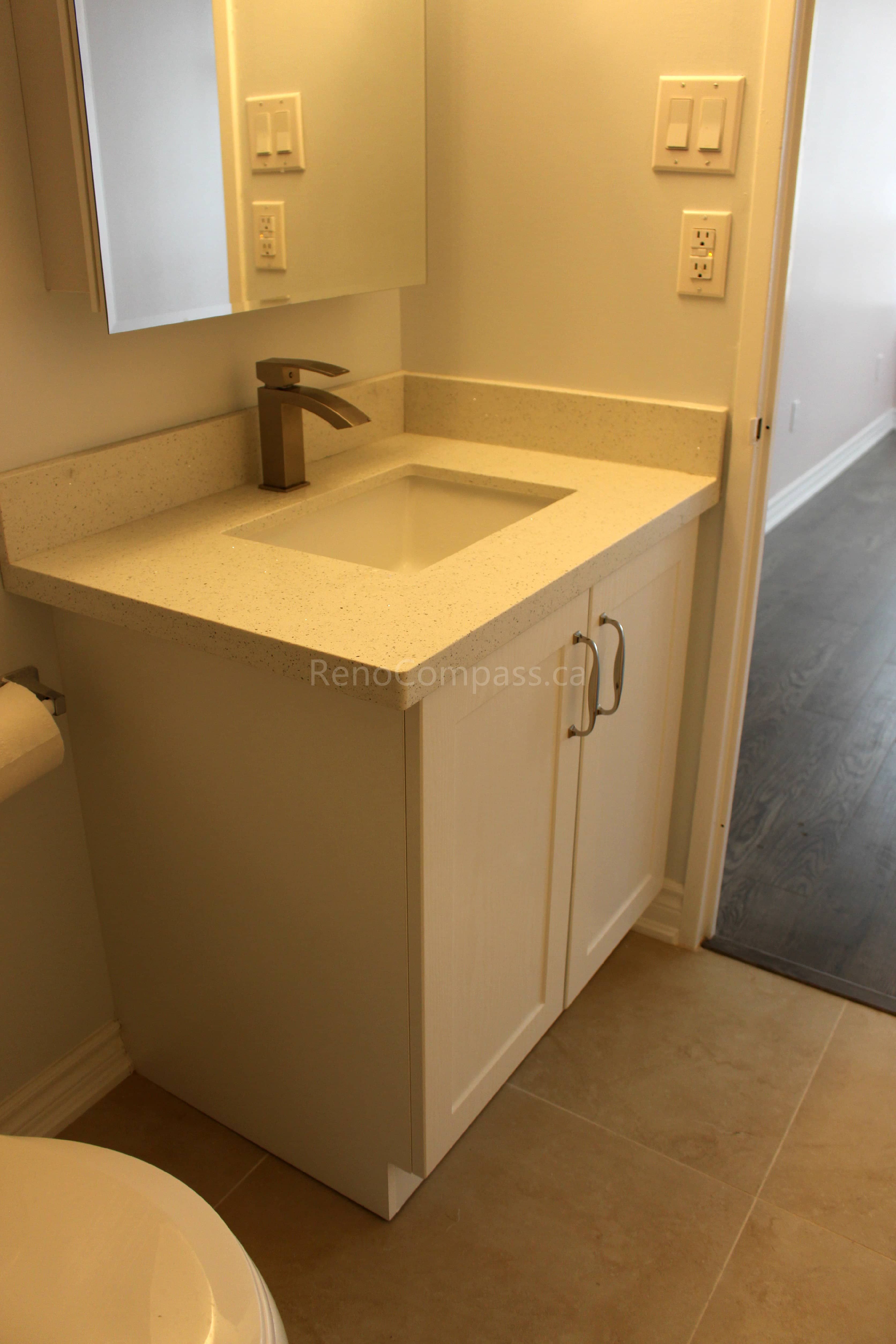 A sleek modern bathroom vanity featuring a white quartz countertop, under-mount sink, and brushed nickel faucet. This updated design enhances both style and functionality, part of a full Mississauga home renovation by RenoCompass.