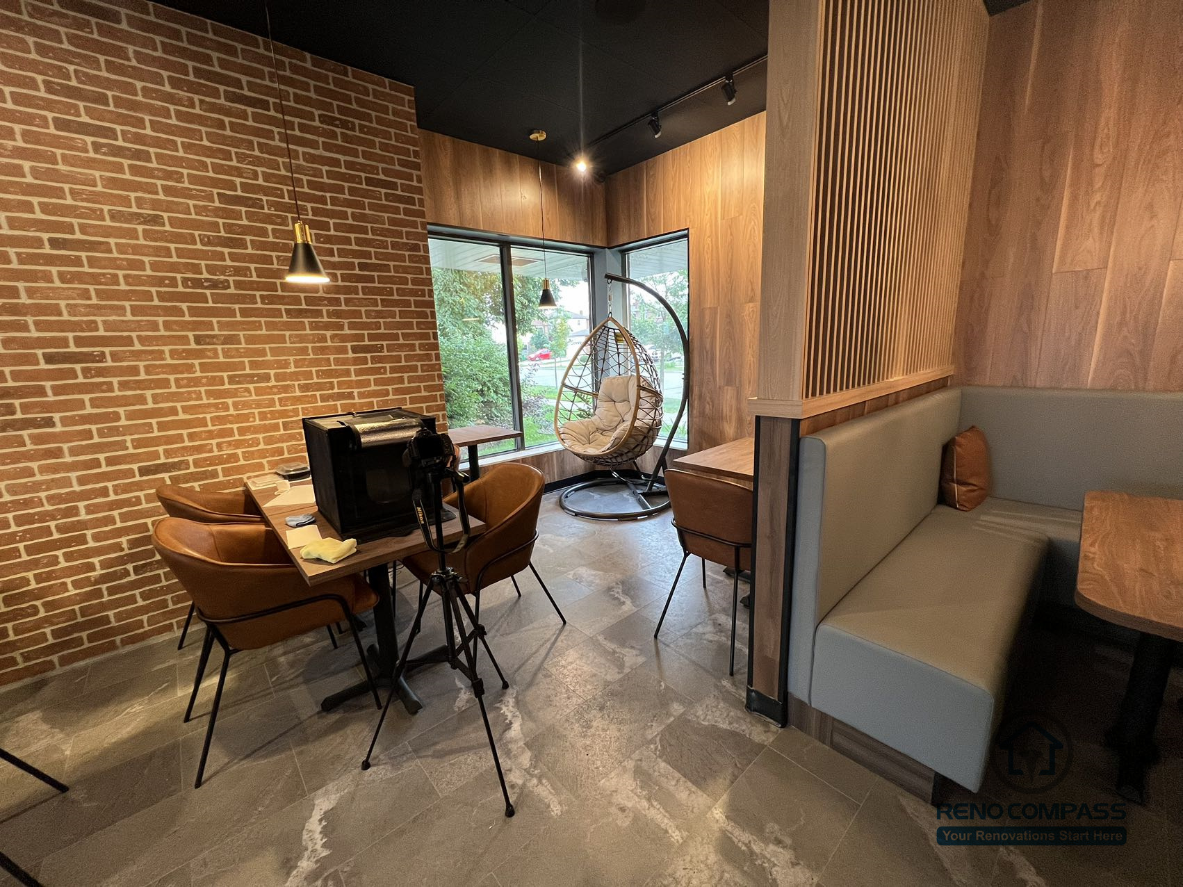 This Mississauga restaurant renovation features a cozy window-side seating and lounge area with warm wood wall finishes, pendant lighting, and natural daylight. The space creates a relaxed dining atmosphere that enhances customer comfort and overall restaurant experience.