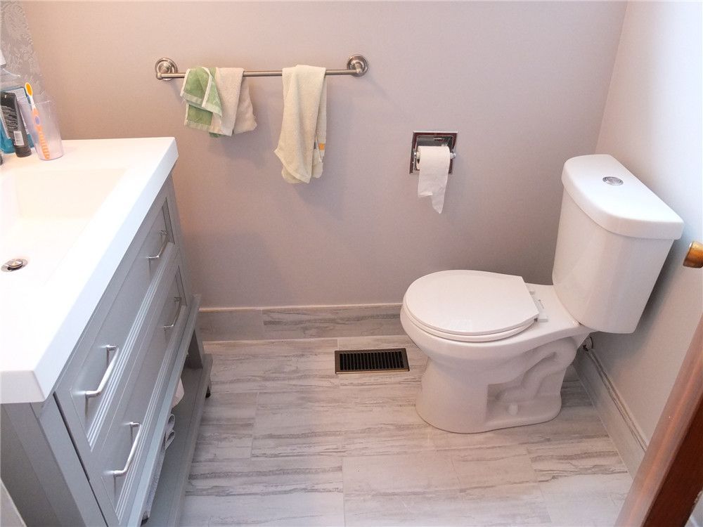 This bathroom renovation in North York features a modern vanity with a quartz countertop, under-mount sink, brushed nickel faucet, and framed mirror with warm wall lighting. The updated design improves both functionality and visual comfort, creating a clean and elegant bathroom space. Completed by a professional Toronto renovation team, the project focuses on quality finishes, practical storage, and timeless interior style.