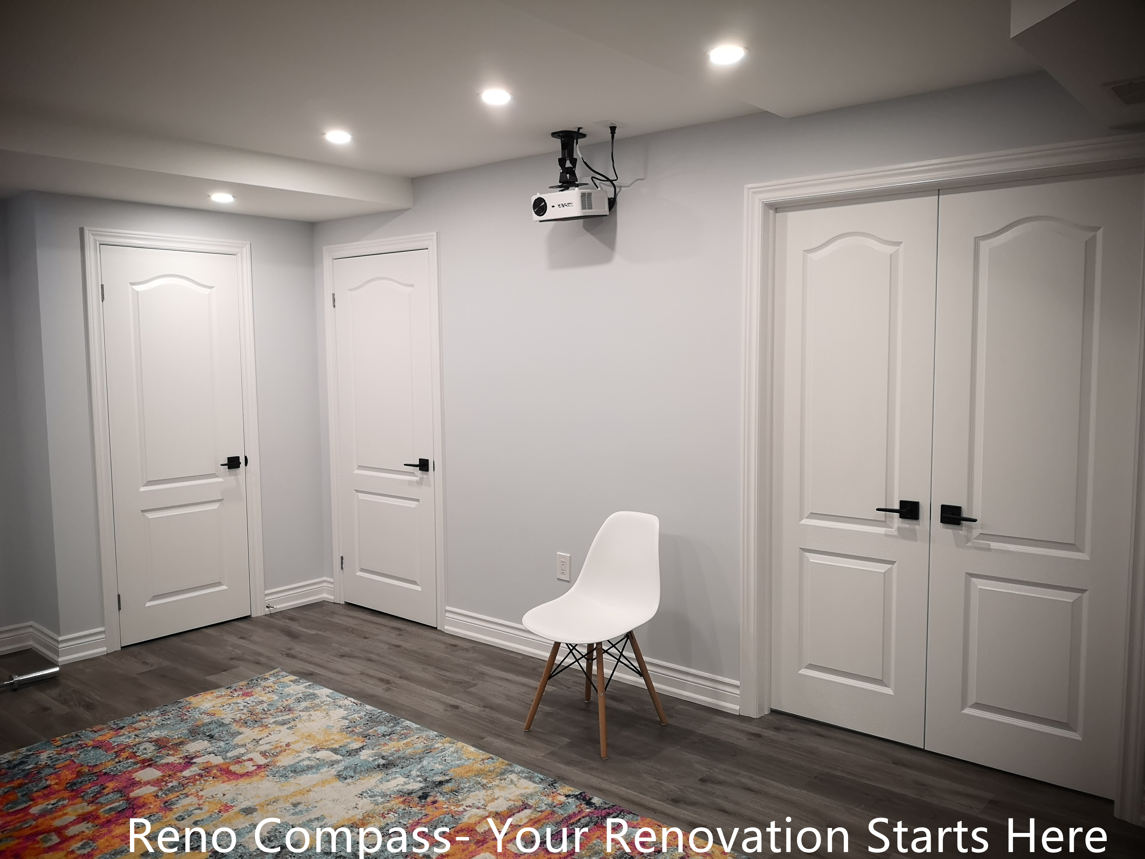 This Whitby basement renovation features a multi-purpose room designed to support entertainment, recreation, or flexible everyday use. The space includes multiple interior doors providing access to storage or utility areas, helping keep the basement organized and clutter-free. Wood-look flooring and neutral wall finishes maintain a clean, modern appearance, while recessed ceiling lights ensure balanced illumination. The layout allows easy adaptation for uses such as a home theater, fitness area, or hobby space, highlighting the practicality and versatility of the finished basement design.