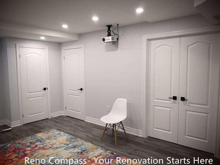 This Whitby basement renovation features a multi-purpose room designed to support entertainment, recreation, or flexible everyday use. The space includes multiple interior doors providing access to storage or utility areas, helping keep the basement organized and clutter-free. Wood-look flooring and neutral wall finishes maintain a clean, modern appearance, while recessed ceiling lights ensure balanced illumination. The layout allows easy adaptation for uses such as a home theater, fitness area, or hobby space, highlighting the practicality and versatility of the finished basement design.