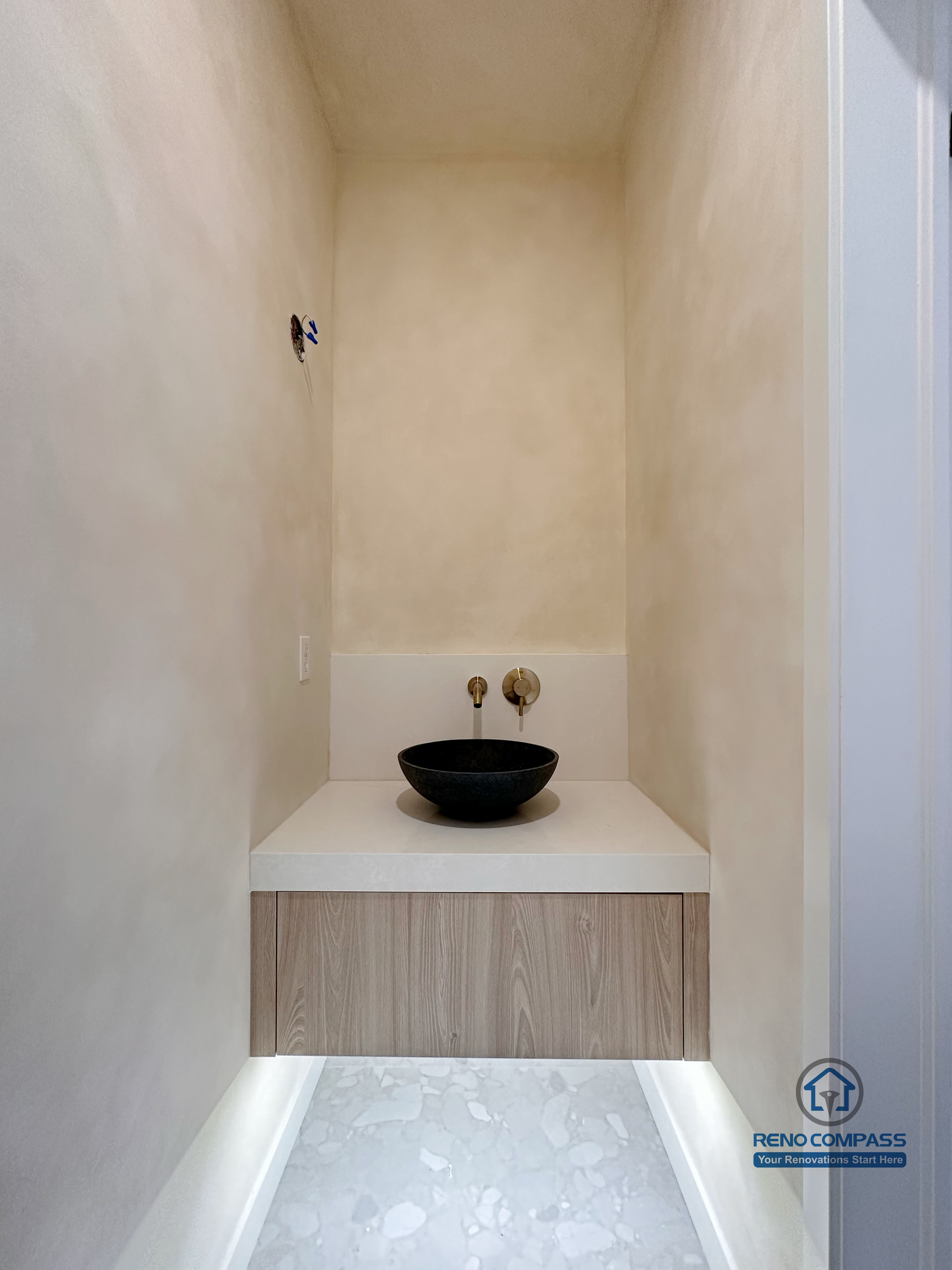 Custom bathroom vanity niche in a Markham renovation project, featuring a floating wood vanity, vessel sink, and integrated under-cabinet lighting. The compact layout and minimalist finishes create a refined, modern powder room detail with strong visual focus and practical functionality.