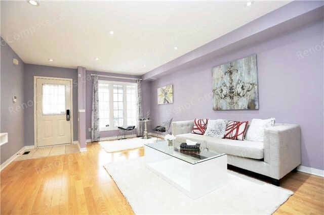 A bright and modern living room renovation featuring soft lavender walls, sleek hardwood flooring, and a contemporary white sofa. A stylish and inviting home interior upgrade in Toronto.