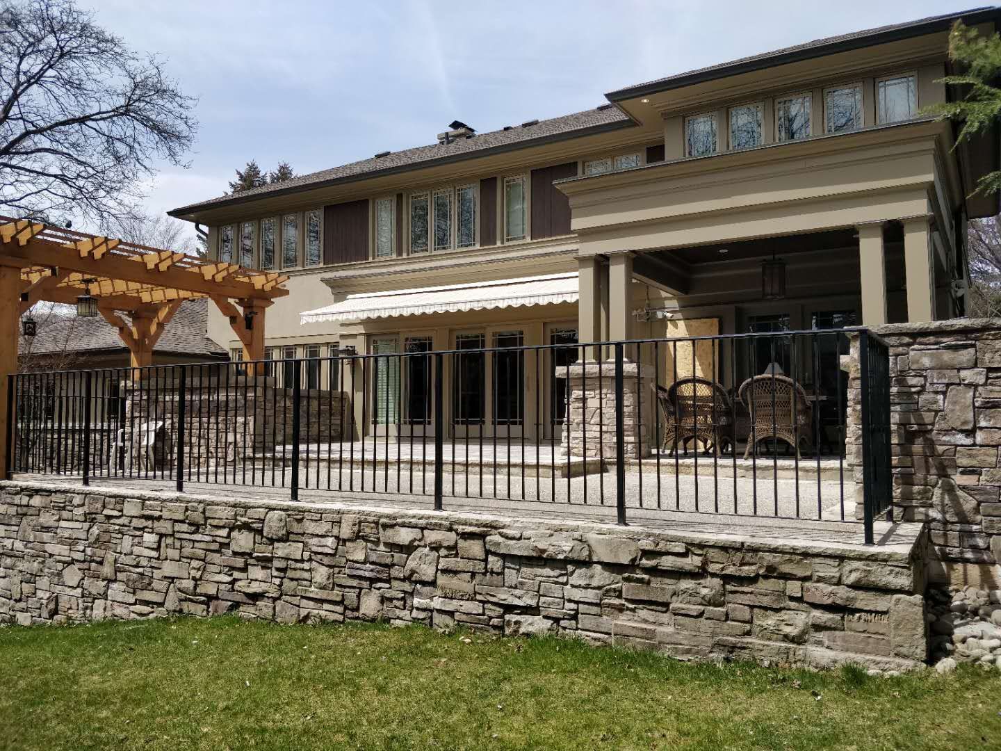 Oakville backyard renovation featuring a spacious interlock stone patio, custom pergola, and stone column detailing. Designed to create a durable, low-maintenance outdoor living and entertaining area.