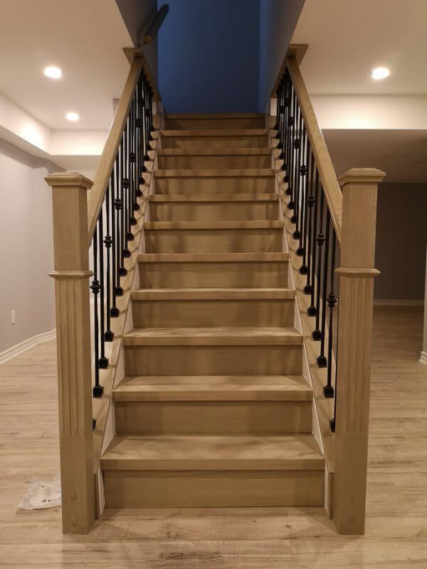 This Markham basement renovation project showcases a modern staircase upgrade with natural wood steps, black iron balusters, and newly installed light-toned flooring. Completed by a professional Toronto renovation company, the finished basement features improved layout flow, clean finishes, and a bright, comfortable living space ideal for modern family use.