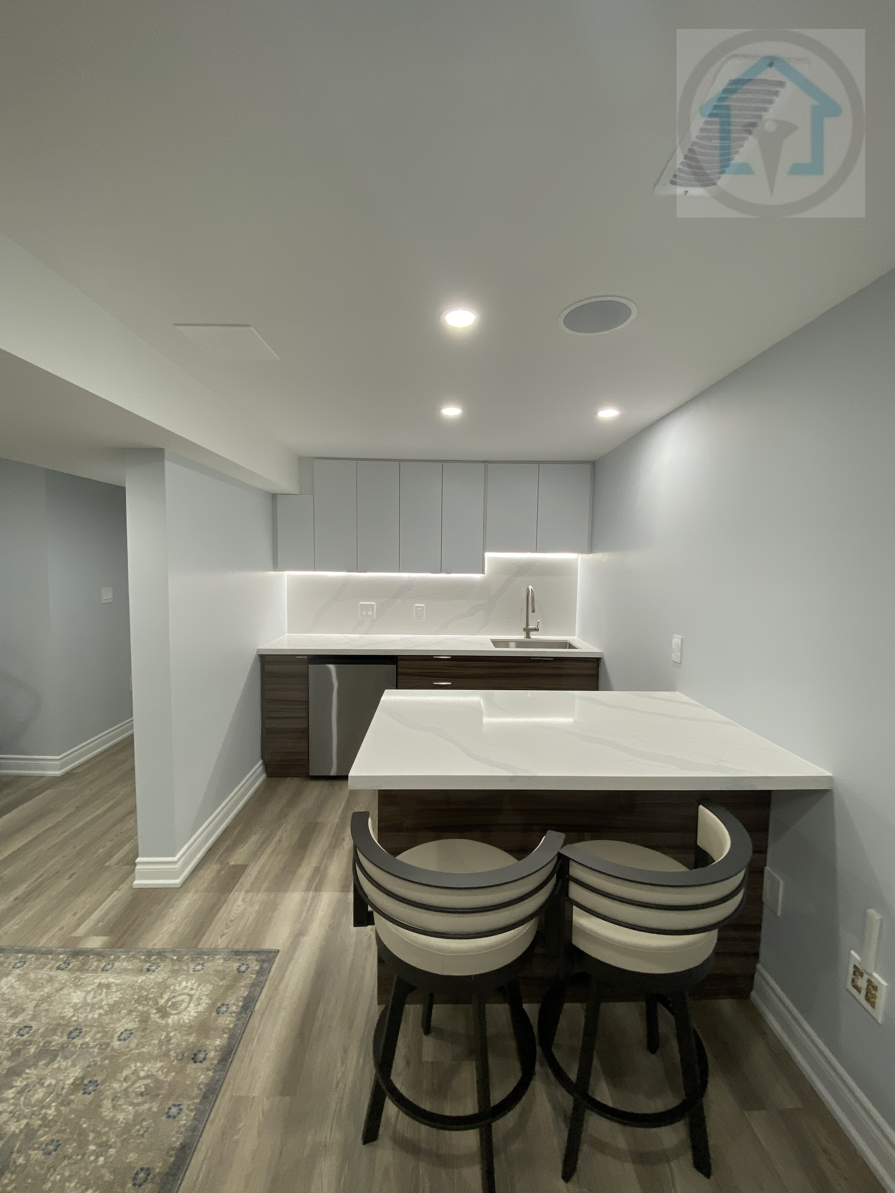 This Vaughan basement renovation features a modern kitchen bar with island seating, clean-lined cabinetry, and integrated lighting. The compact layout maximizes functionality while maintaining clear circulation, making the basement kitchen area suitable for casual dining, entertaining, and everyday use.