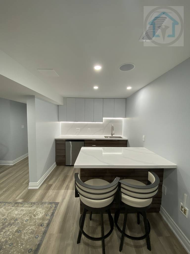 This Vaughan basement renovation features a modern kitchen bar with island seating, clean-lined cabinetry, and integrated lighting. The compact layout maximizes functionality while maintaining clear circulation, making the basement kitchen area suitable for casual dining, entertaining, and everyday use.