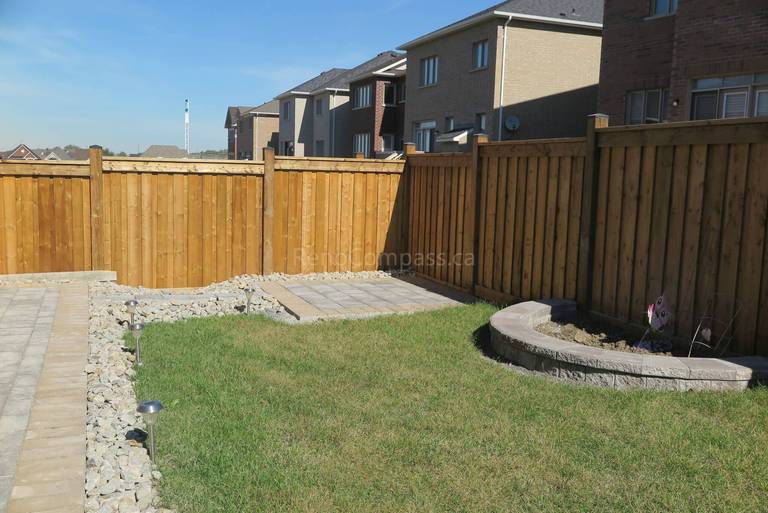 Custom curved garden bed and retaining wall completed in this Aurora backyard landscaping project. The stone border design creates a clean planting area against the wooden fence while maintaining a modern and low-maintenance outdoor layout. Professionally installed by Reno Compass Inc., a trusted Toronto landscaping and renovation contractor serving Aurora and the GTA.
