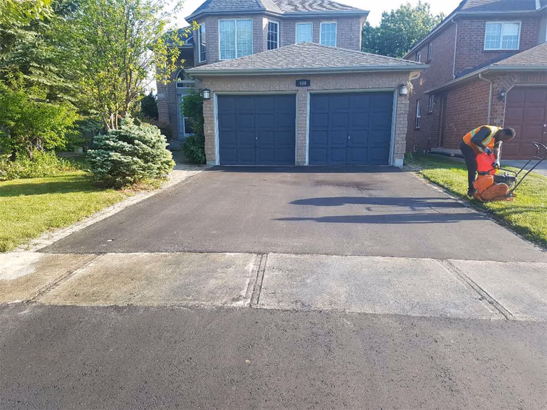 A high-quality asphalt paving installation completed as part of a comprehensive Toronto landscaping renovation. This image shows the smooth, finished surface of a wide driveway, highlighting professional workmanship and curb appeal enhancement.