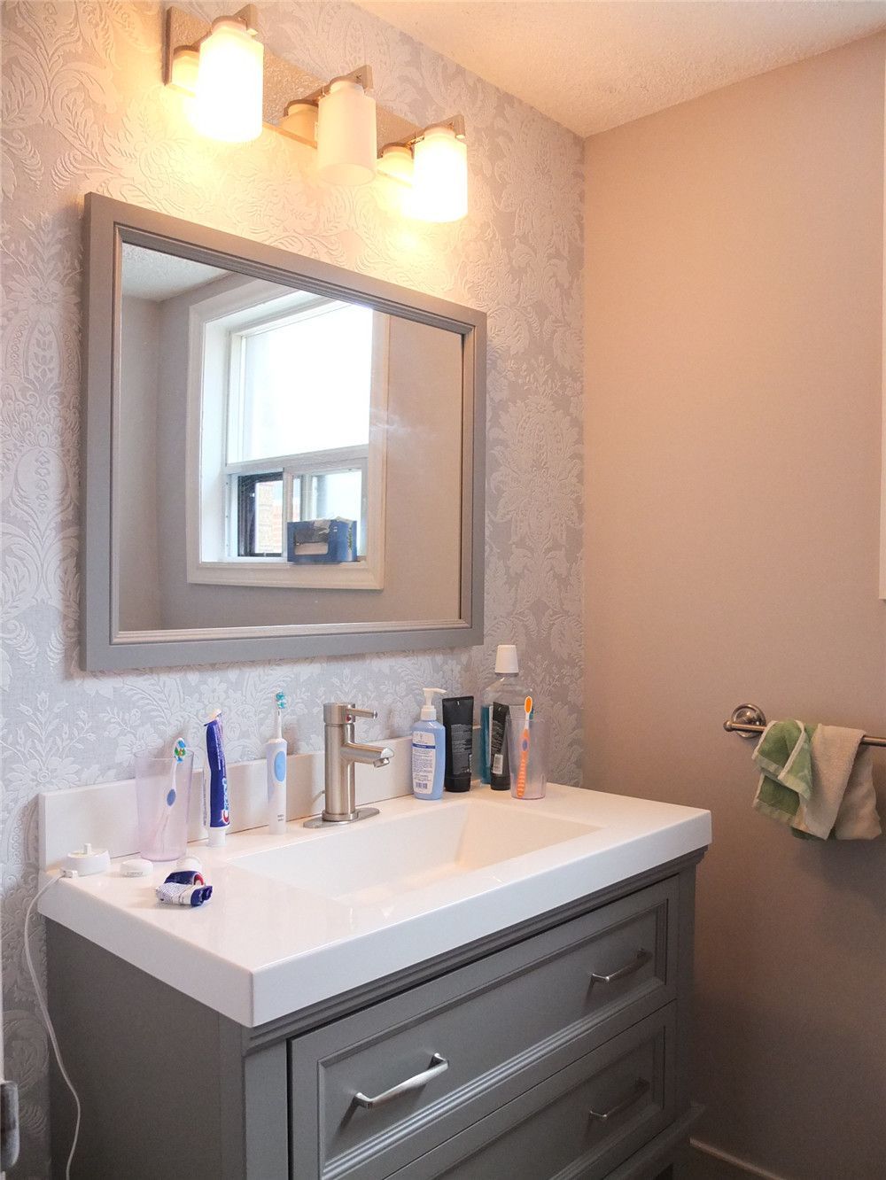 This bathroom renovation in North York features a modern vanity with a quartz countertop, under-mount sink, brushed nickel faucet, and framed mirror with warm wall lighting. The updated design improves both functionality and visual comfort, creating a clean and elegant bathroom space. Completed by a professional Toronto renovation team, the project focuses on quality finishes, practical storage, and timeless interior style.