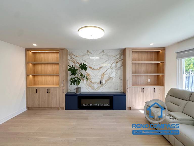 A modern living room featuring custom built-in shelving, a marble fireplace feature wall, integrated electric fireplace, and custom wood cabinetry with ambient lighting. Completed as part of a luxury whole home renovation in Markham, Ontario, this contemporary living space combines elegant storage, premium finishes, and expert craftsmanship by Reno Compass.