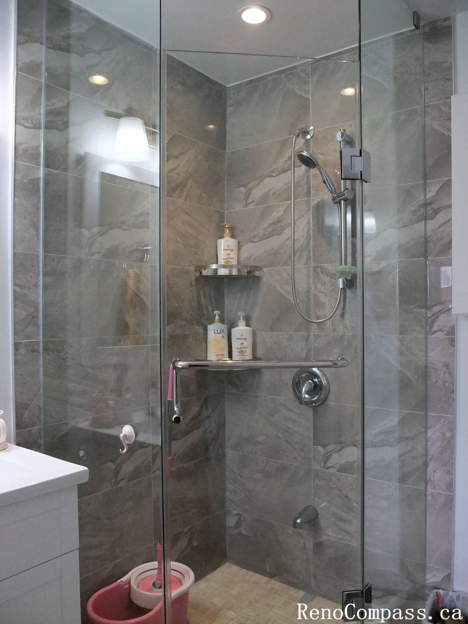 Bathroom interior renovation in North York featuring a frameless glass shower, marble-look porcelain tiles, built-in shower shelf, and modern chrome fixtures. This Toronto interior renovation emphasizes clean lines, functional storage, and durable materials for everyday residential use.