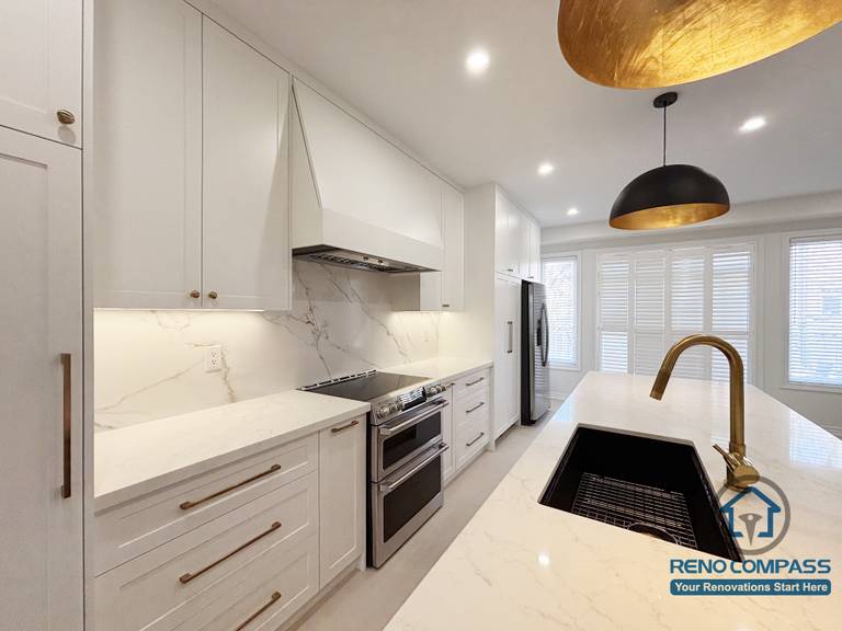 This Oakville kitchen renovation highlights the relationship between the main cooking zone and the island sink, creating a practical and efficient workspace for everyday use. The continuous backsplash, built-in hood, and clean-lined cabinetry establish a cohesive cooking area, while the island supports preparation and cleanup without interrupting circulation. Balanced lighting and durable surfaces reinforce a calm, functional kitchen environment. Completed by Reno Compass, this design reflects a well-considered approach to modern Oakville kitchen renovation focused on long-term usability.