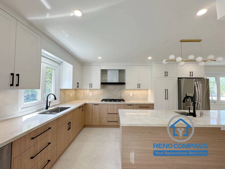 A custom kitchen featuring a large quartz island, two-tone cabinetry, under-cabinet LED lighting, premium stainless steel appliances, and a spacious work triangle. Completed during a luxury whole home renovation in Markham, Ontario, this modern kitchen blends timeless design, functional storage, and exceptional craftsmanship by Reno Compass.