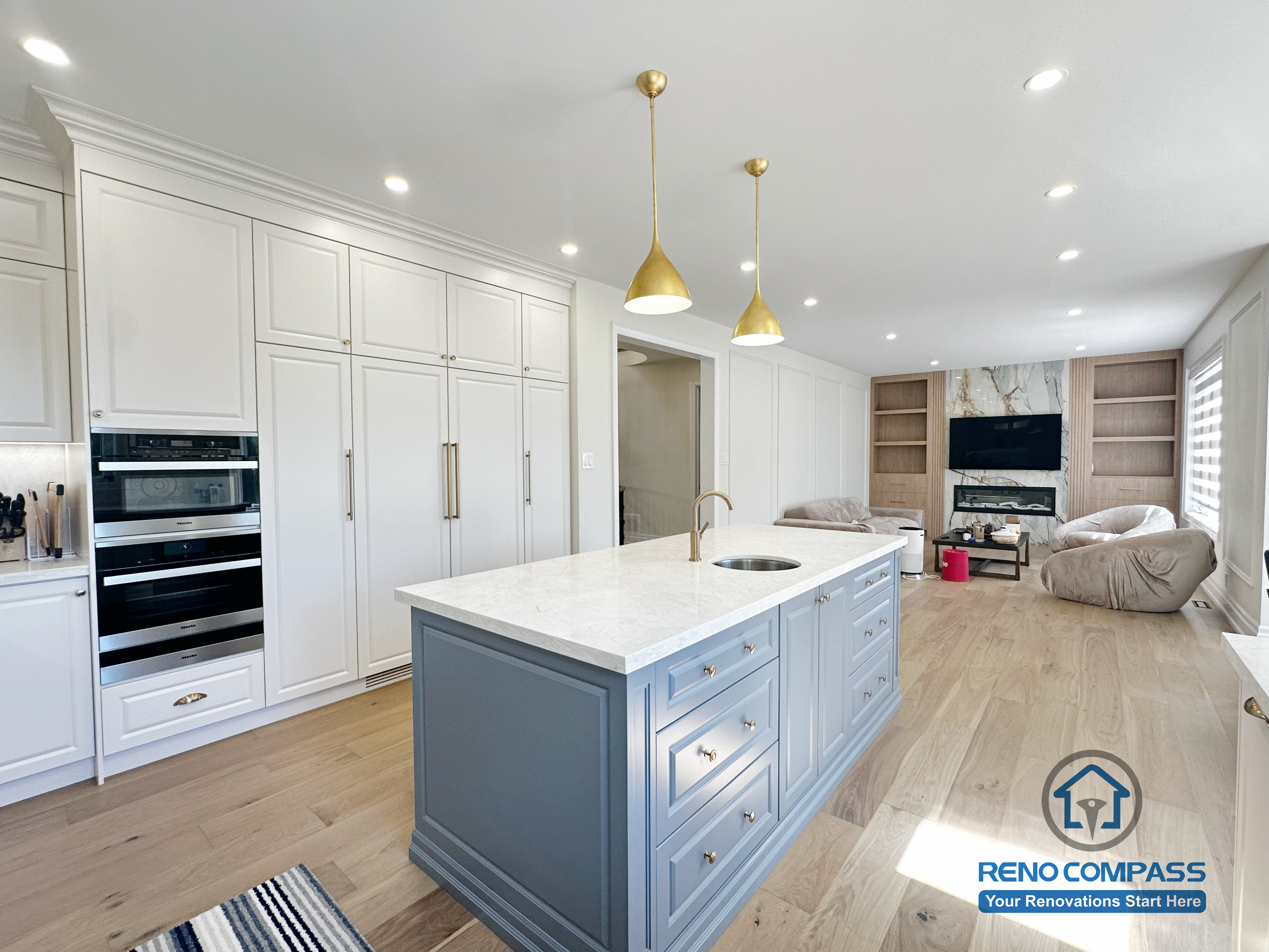 This North York kitchen renovation highlights a custom blue island with integrated drawers, full-height built-in cabinetry, and balanced recessed and pendant lighting. The layout maximizes storage efficiency while maintaining clean lines and visual symmetry, creating a refined and highly functional kitchen space designed and built by Reno Compass.