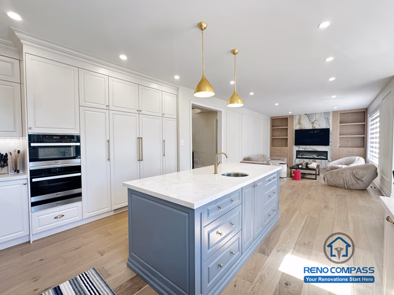 This North York kitchen renovation highlights a custom blue island with integrated drawers, full-height built-in cabinetry, and balanced recessed and pendant lighting. The layout maximizes storage efficiency while maintaining clean lines and visual symmetry, creating a refined and highly functional kitchen space designed and built by Reno Compass.