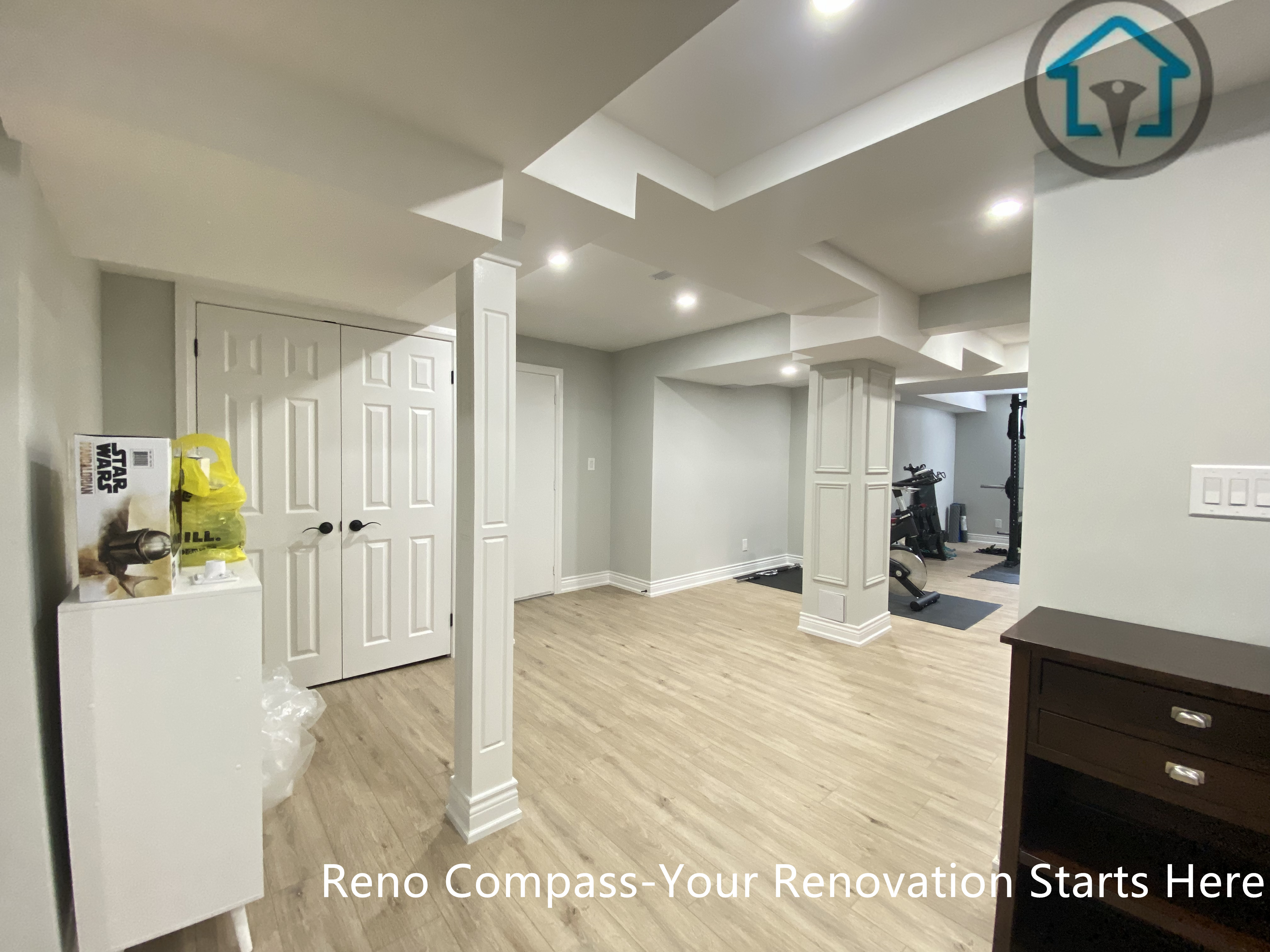 This Stouffville basement renovation highlights an open-concept layout with finished structural columns, clean ceiling detailing, recessed lighting, and continuous wood-look flooring.