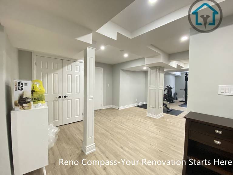 This Stouffville basement renovation highlights an open-concept layout with finished structural columns, clean ceiling detailing, recessed lighting, and continuous wood-look flooring.