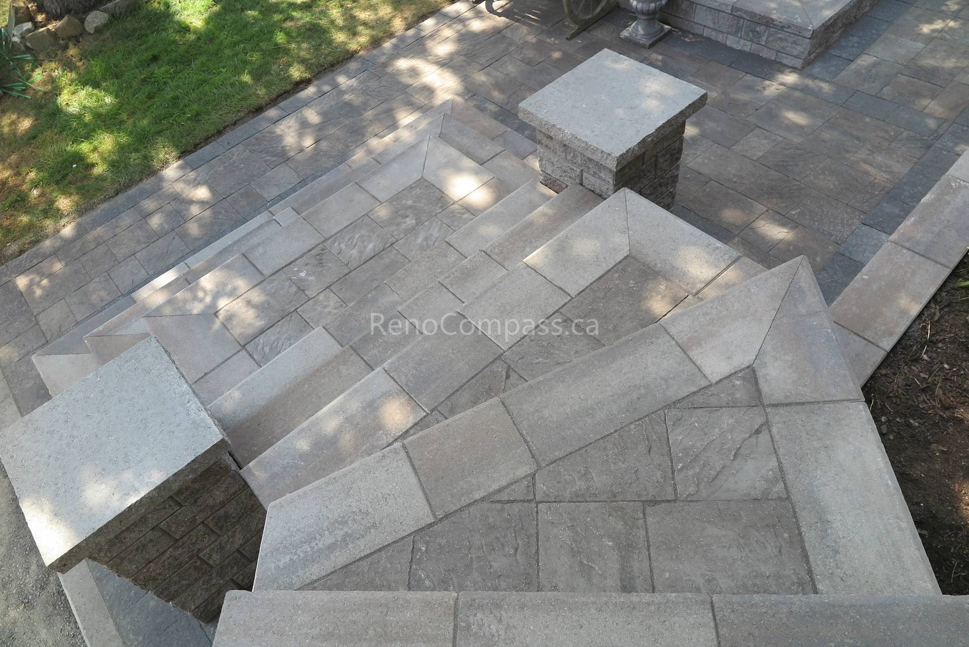 This Mississauga landscaping renovation showcases custom interlocking front entrance steps and landing patio designed for both visual impact and functionality. The multi-level stone layout creates a smooth transition from driveway to entrance while enhancing safety and flow. Premium interlocking pavers and stone columns add depth, structure, and a refined architectural feel to the exterior. Completed by Reno Compass Inc., this project highlights expert craftsmanship in residential interlocking and front yard landscaping design.