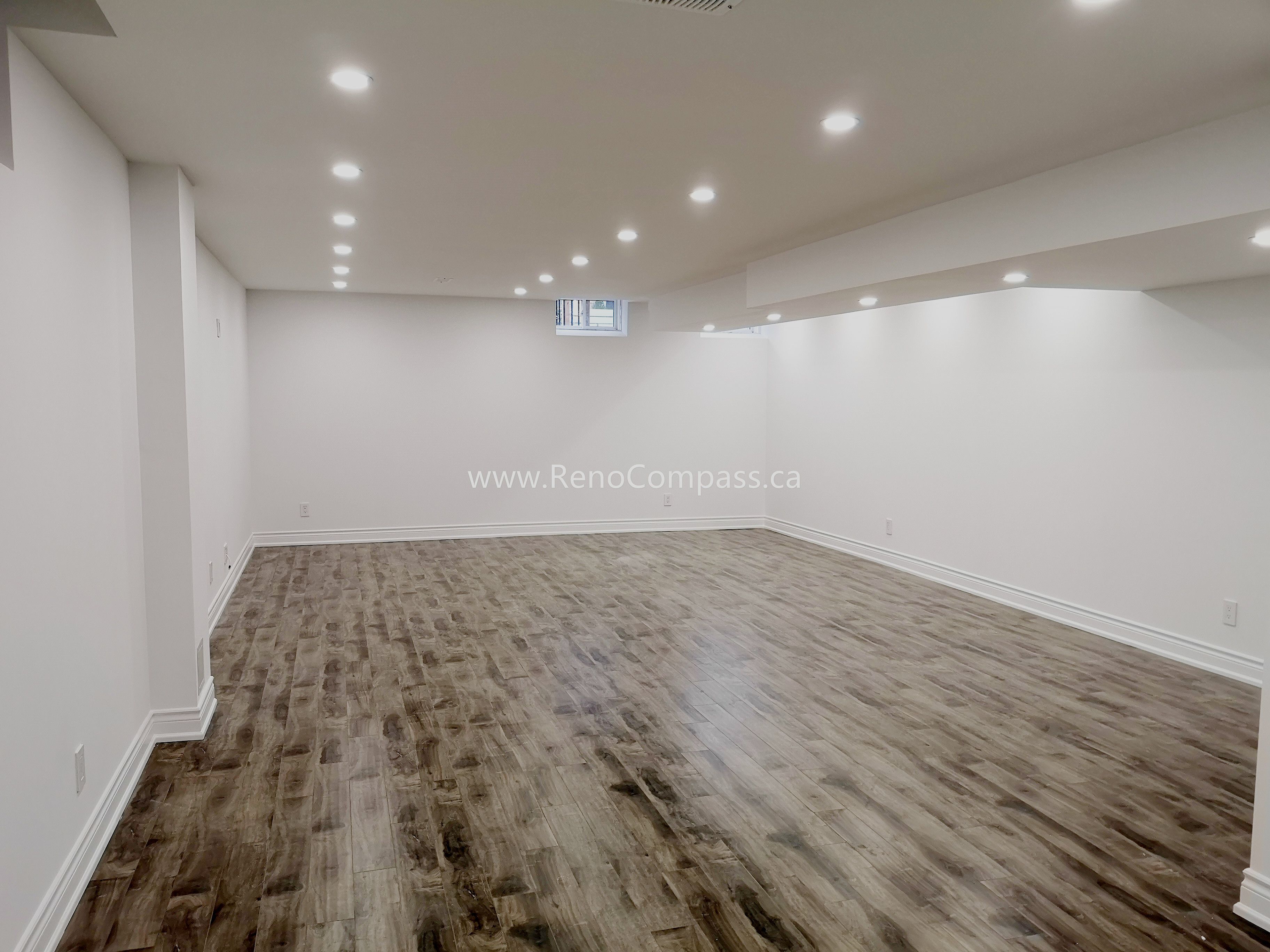 This Vaughan basement renovation project features a spacious open-concept layout with modern recessed lighting, upgraded flooring, and clean white wall finishes. The newly renovated basement offers a bright and functional living space ideal for entertainment, family use, or rental potential. Completed by Reno Compass Inc., this project highlights high-quality craftsmanship and efficient space planning, transforming an unfinished basement into a comfortable and modern extension of the home.