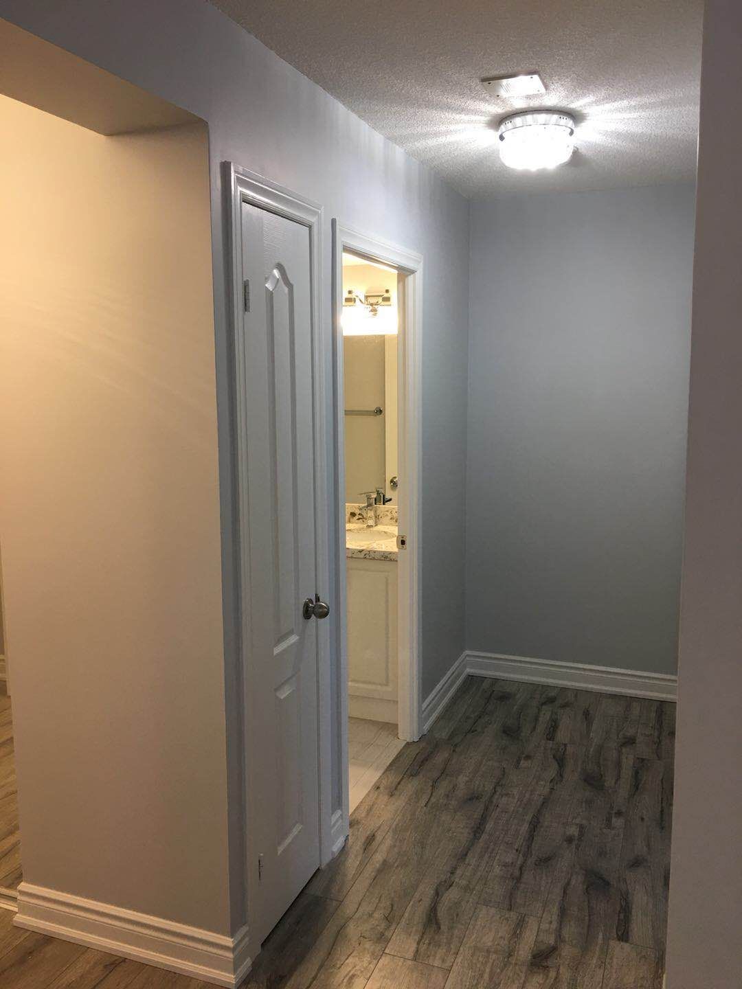 This Toronto interior renovation project showcases a refreshed hallway space featuring durable wood-look flooring, newly painted walls, updated trim, and modern ceiling lighting. The renovation improves brightness and flow between rooms while creating a clean and cohesive look for the home's interior layout.