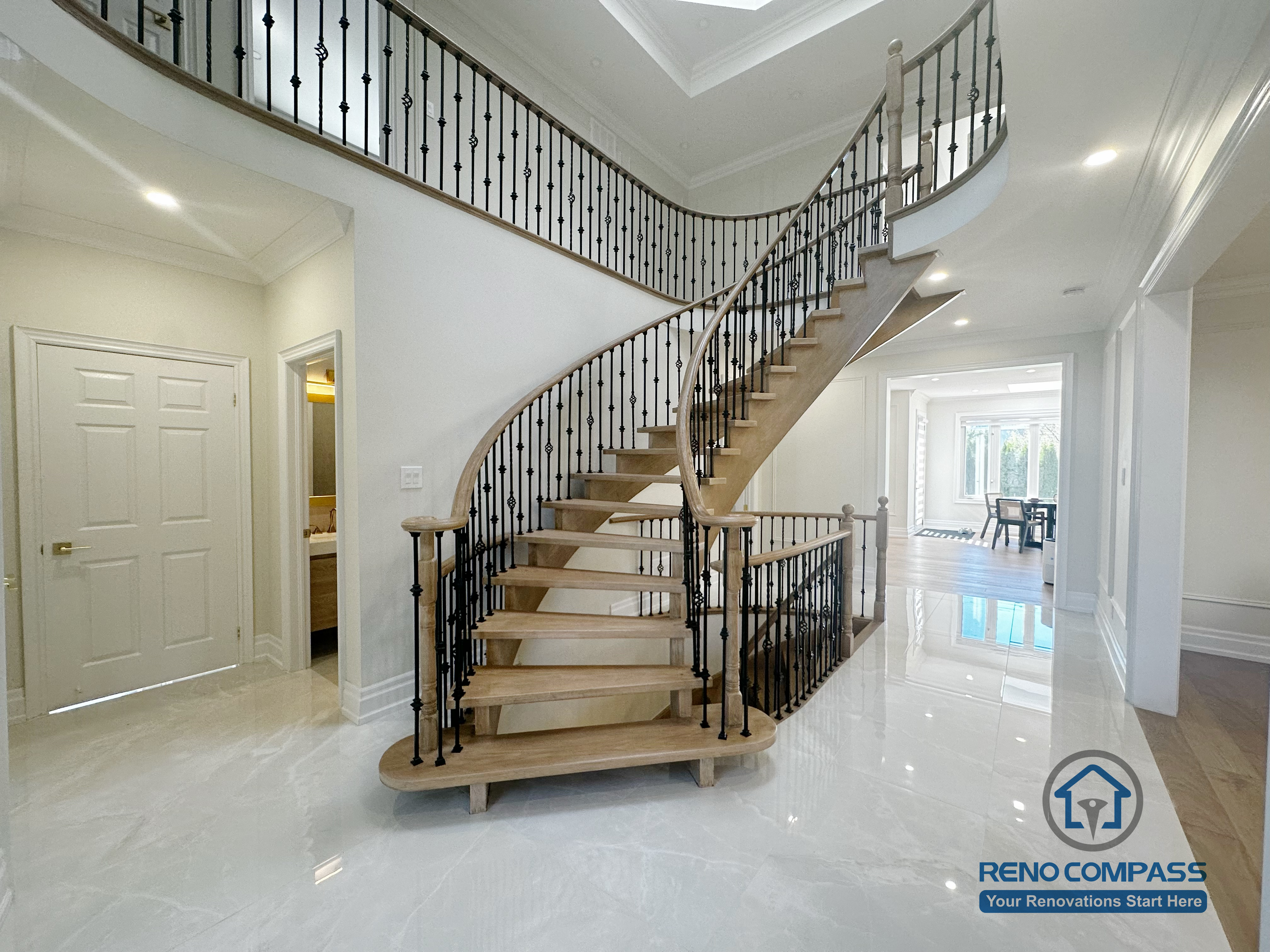 This image showcases the front view of a grand curved staircase as part of a North York flooring and stair renovation. The staircase features solid hardwood treads, smooth curved stringers, and decorative iron balusters, forming a strong architectural focal point at the home’s entrance. The surrounding flooring is finished with polished, light-toned surfaces that enhance brightness and reflect natural light. This renovation highlights precise craftsmanship and seamless coordination between flooring and stair design, creating an elegant and cohesive interior for North York homes.