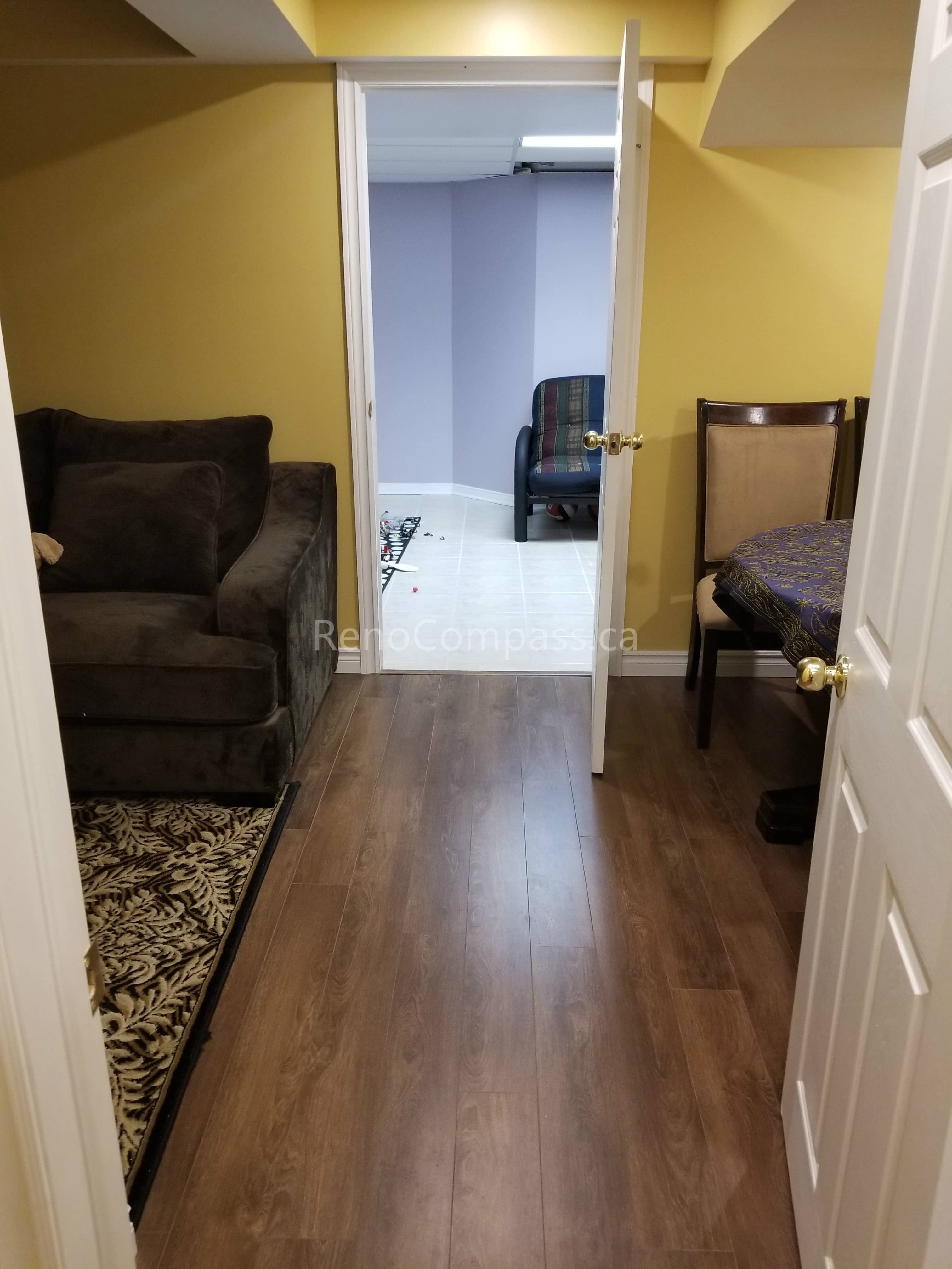 This Vaughan basement renovation showcases a refreshed living area with newly installed wood-look flooring, updated lighting, and a functional layout that connects multiple rooms seamlessly. The warm wall tones and durable flooring create a comfortable and inviting basement environment suitable for relaxation, entertainment, or extended living space. Completed by Reno Compass Inc., this basement upgrade enhances both practicality and modern appeal for everyday use.