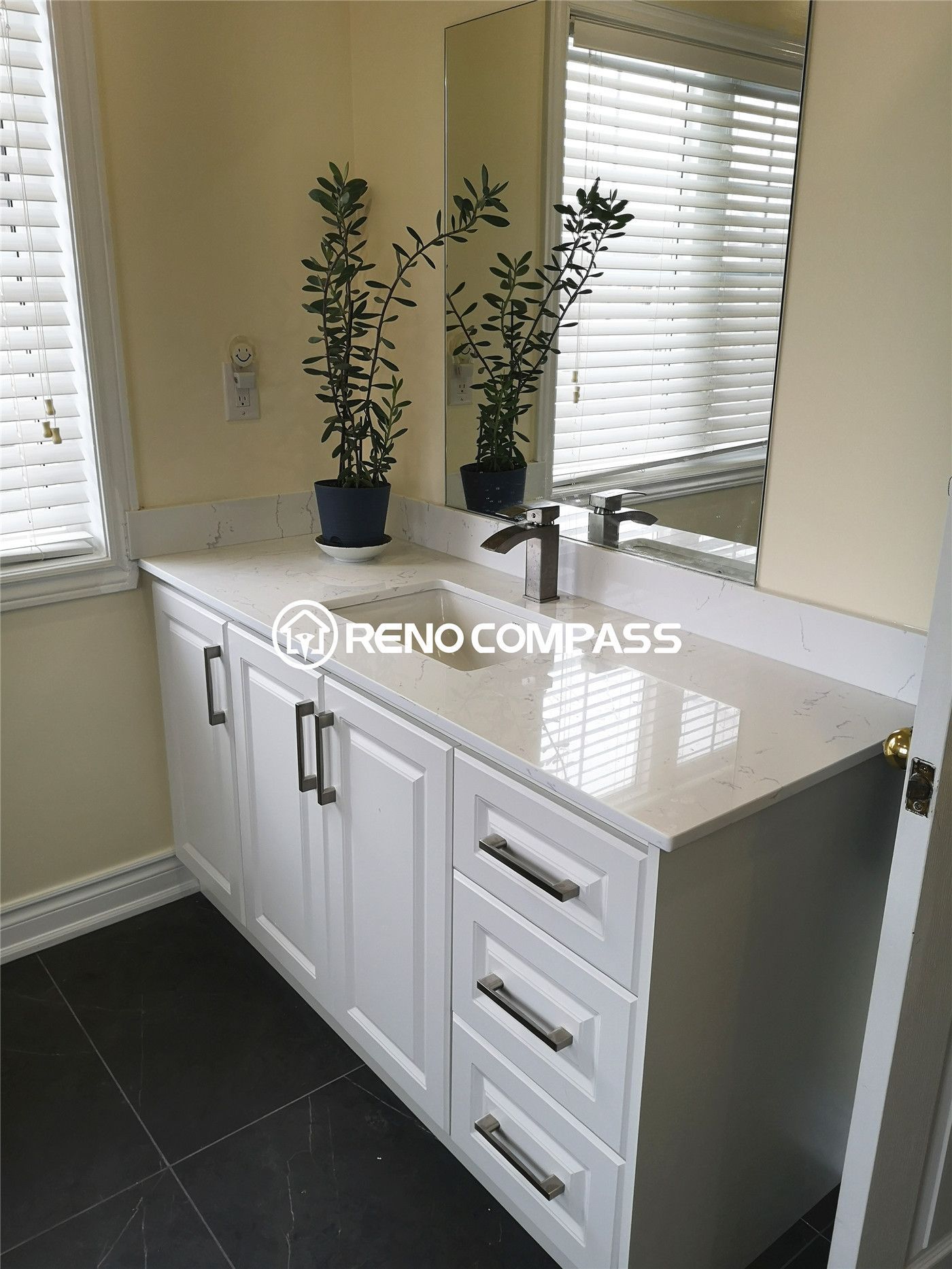 A bright and modern bathroom vanity installation in Richmond Hill featuring a sleek white cabinet, quartz countertop, and chrome faucet. Accented with greenery for a fresh, inviting look — another quality renovation by Reno Compass.