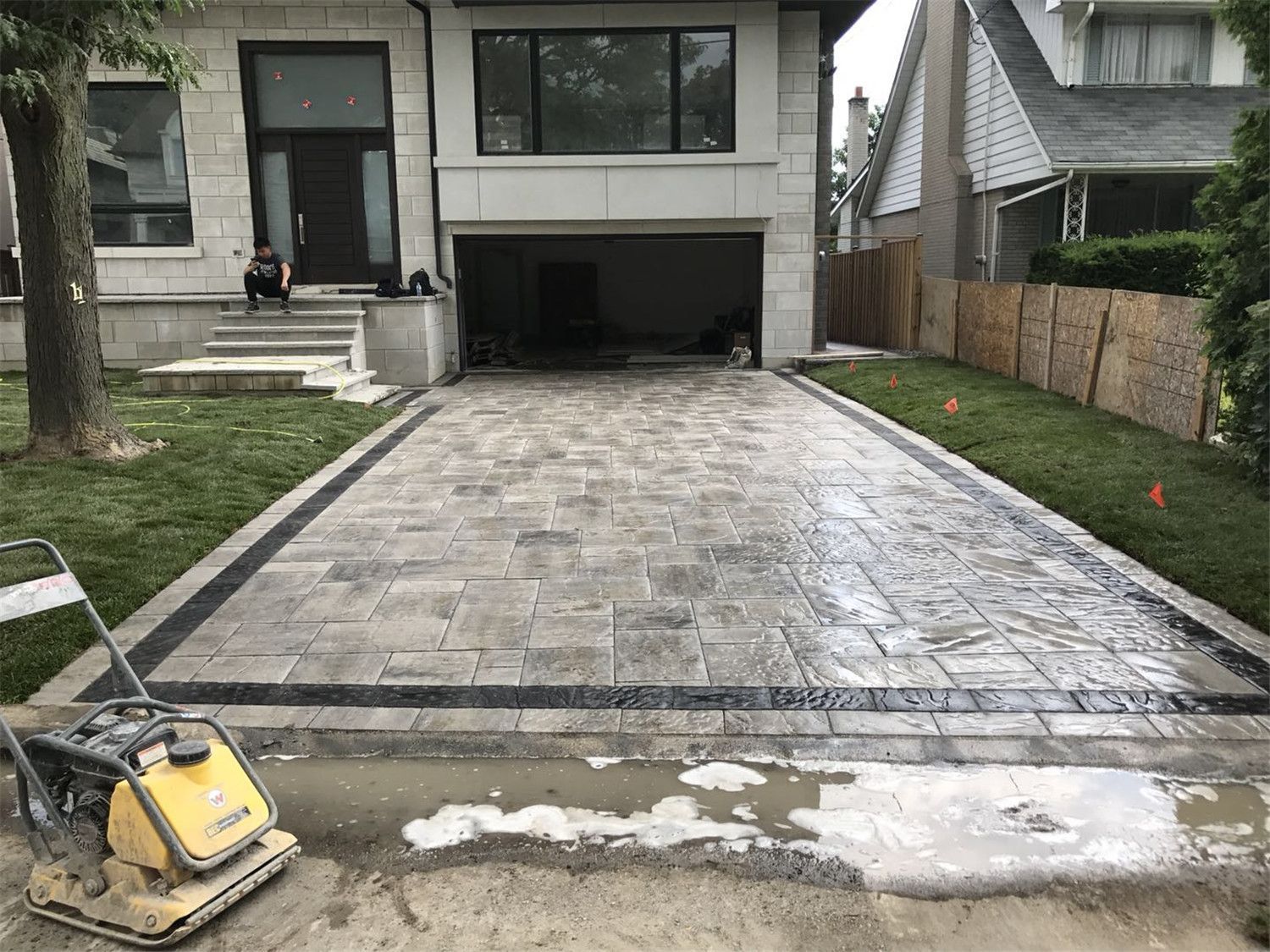 Front yard landscaping renovation in Toronto featuring a large interlocking driveway with decorative stone borders and clean modern paving patterns. The project improves curb appeal while providing a durable and functional driveway surface for everyday use.