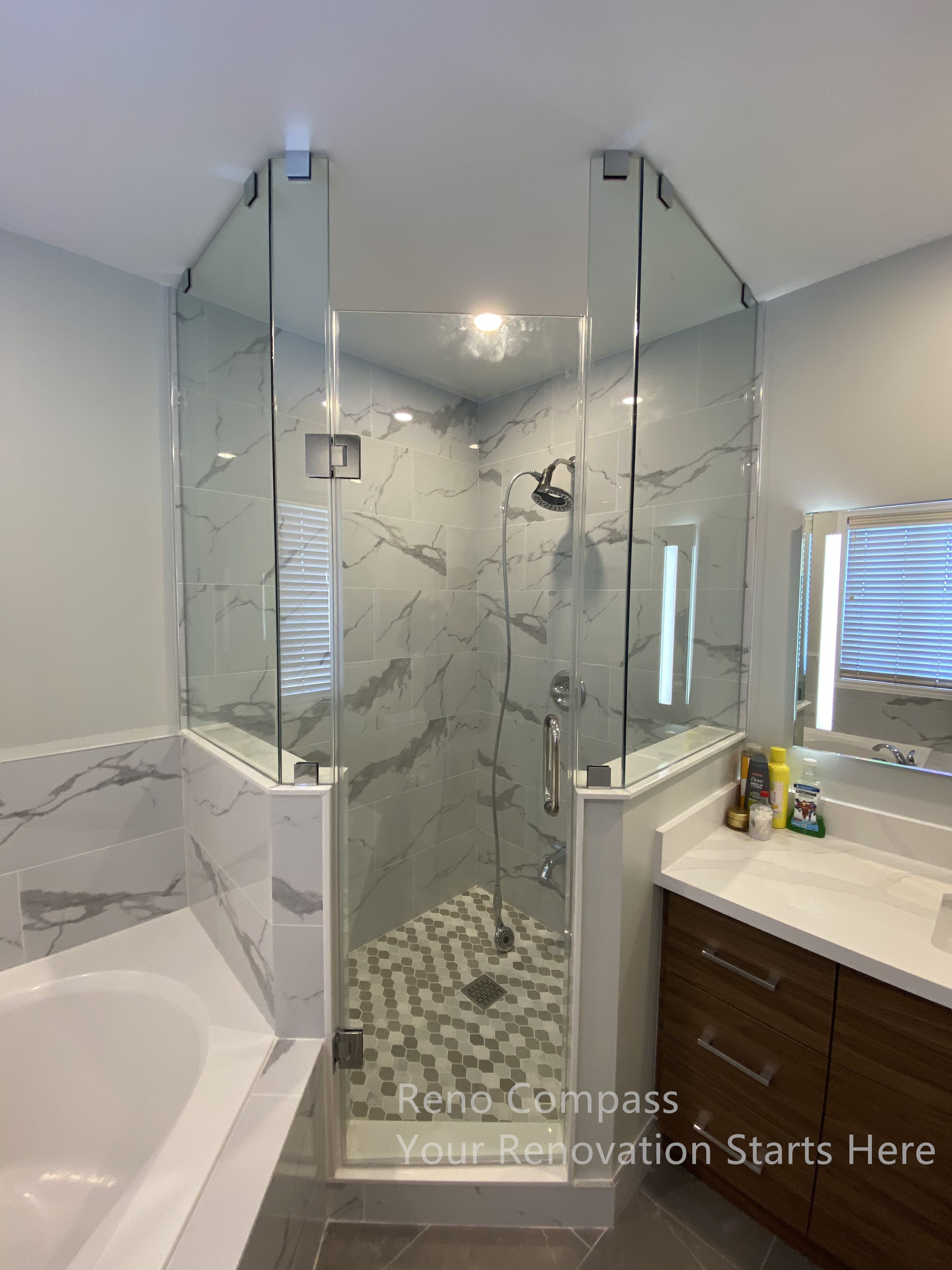This Newmarket bathroom renovation features a custom glass shower enclosure paired with marble-look wall tiles and a patterned shower floor for added texture and visual interest. The frameless glass panels enhance openness while maintaining clear separation between the shower and bathtub areas. Coordinated finishes and clean-lined fixtures create a balanced, modern aesthetic that is both practical and easy to maintain. Thoughtful material selection improves moisture resistance and long-term durability, resulting in a calm, spa-inspired bathroom designed for everyday comfort. This renovation was completed by Reno Compass, serving homeowners in Newmarket and across the GTA.