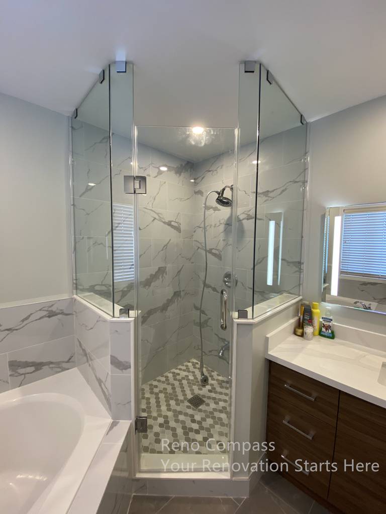 This Newmarket bathroom renovation features a custom glass shower enclosure paired with marble-look wall tiles and a patterned shower floor for added texture and visual interest. The frameless glass panels enhance openness while maintaining clear separation between the shower and bathtub areas. Coordinated finishes and clean-lined fixtures create a balanced, modern aesthetic that is both practical and easy to maintain. Thoughtful material selection improves moisture resistance and long-term durability, resulting in a calm, spa-inspired bathroom designed for everyday comfort. This renovation was completed by Reno Compass, serving homeowners in Newmarket and across the GTA.