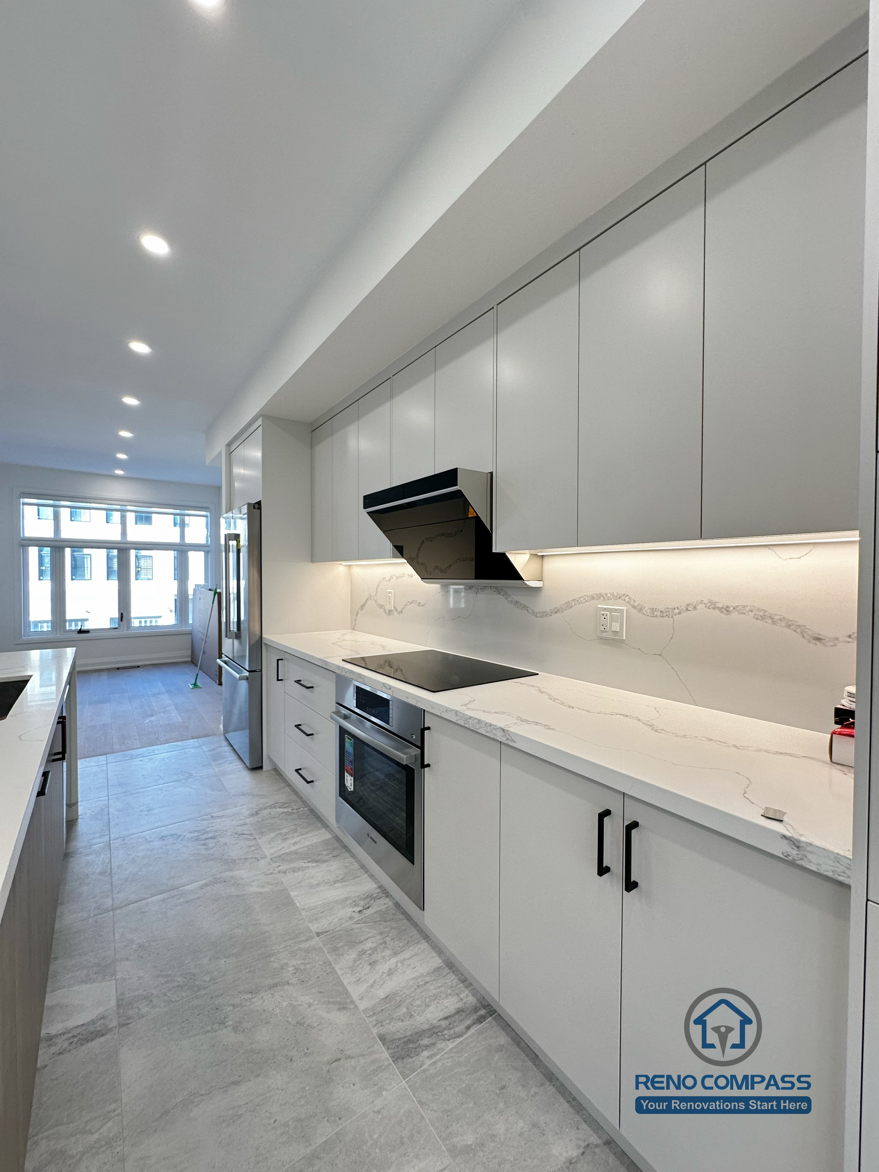 This Richmond Hill kitchen features flat-panel cabinetry, quartz countertops with subtle veining, integrated range hood, and continuous under-cabinet lighting, delivering a streamlined and functional cooking workspace.