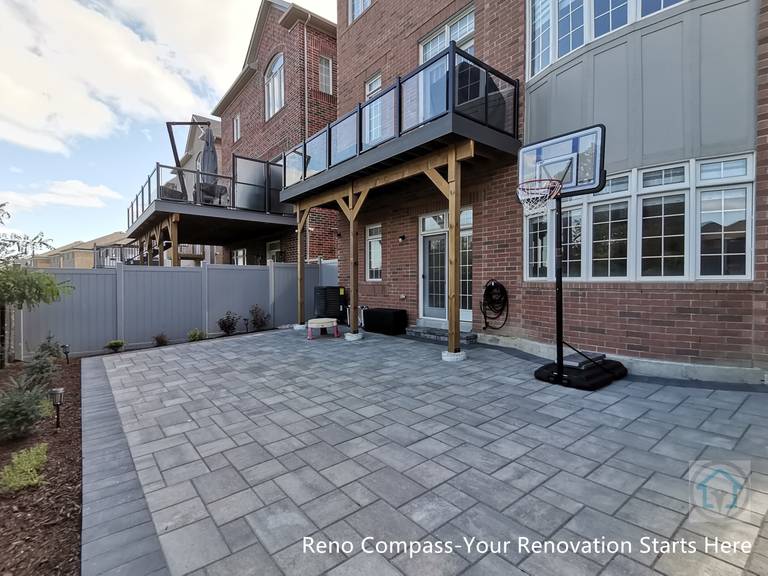 This Vaughan backyard renovation combines a covered wood deck structure with a spacious interlocking stone patio. The elevated deck provides shaded outdoor living space, while the durable paver surface below supports everyday use, play, and entertaining. The design creates a functional, low-maintenance backyard that integrates seamlessly with the home’s architecture.