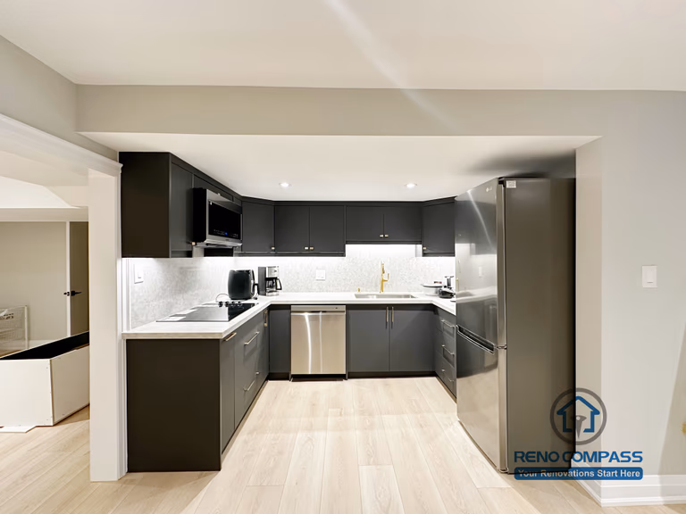 Basement renovation in Richmond Hill featuring a modern kitchenette with matte black cabinetry, stainless steel appliances, quartz-style countertops, and efficient space planning for daily use.