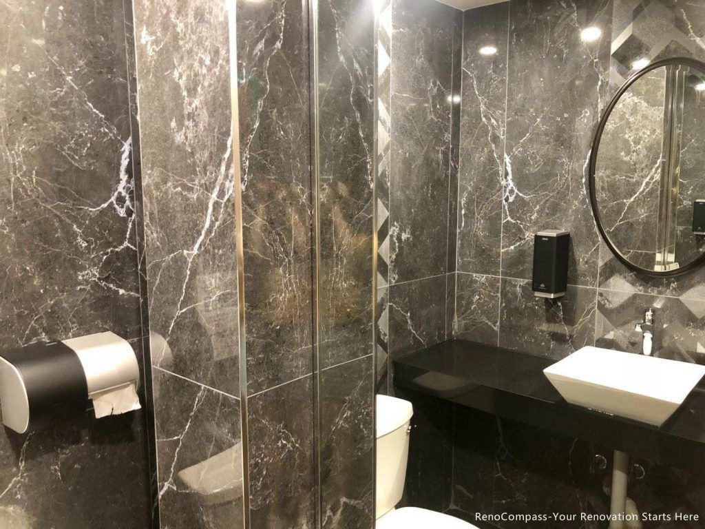This Barrie commercial renovation features a modern washroom design with full marble-style wall tiles, glass shower enclosure, and sleek black countertop vanity. The space combines durability with a high-end aesthetic to enhance customer experience in a commercial setting. Completed by Reno Compass Inc., a professional Toronto renovation company, this project highlights quality workmanship for restaurants, cafés, and retail commercial interiors across Barrie and the GTA.