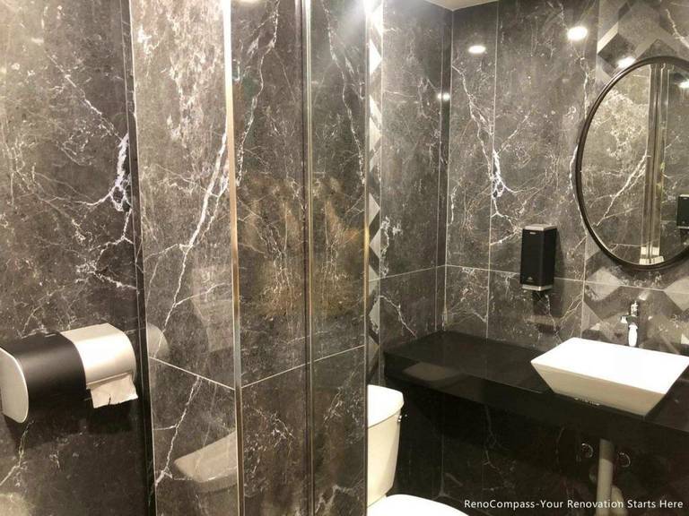 This Barrie commercial renovation features a modern washroom design with full marble-style wall tiles, glass shower enclosure, and sleek black countertop vanity. The space combines durability with a high-end aesthetic to enhance customer experience in a commercial setting. Completed by Reno Compass Inc., a professional Toronto renovation company, this project highlights quality workmanship for restaurants, cafés, and retail commercial interiors across Barrie and the GTA.