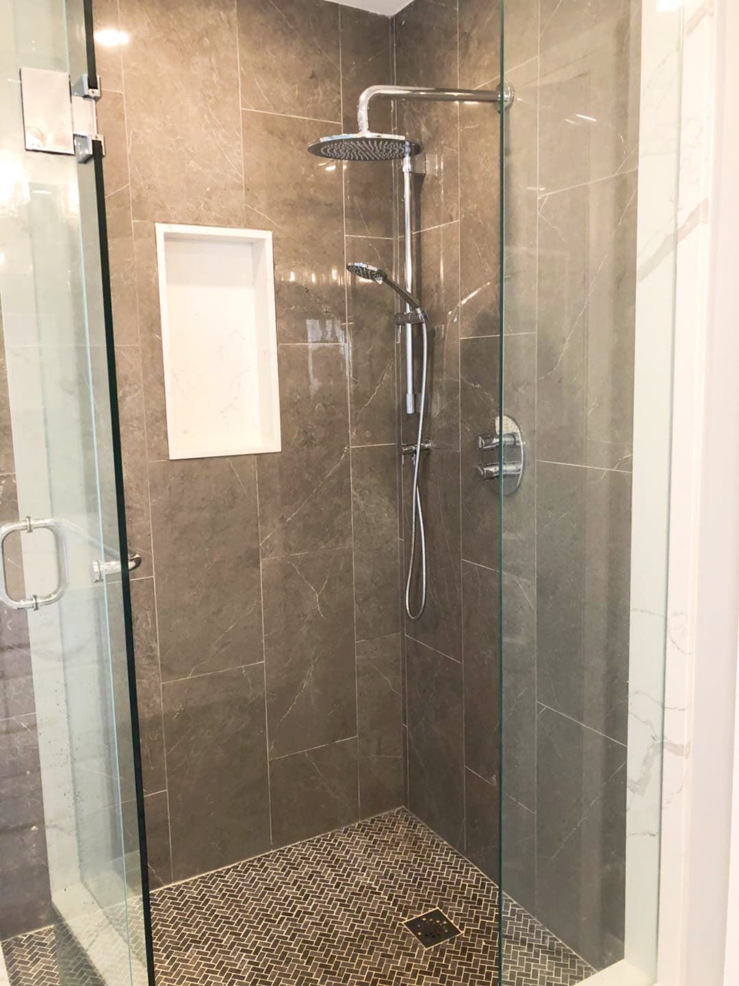 This Richmond Hill bathroom renovation features a modern walk-in glass shower with a sleek rainfall showerhead, built-in wall niche, and textured mosaic shower floor for enhanced safety and style. Large-format wall tiles and a frameless glass enclosure create a clean, open, and contemporary look. The upgraded shower design improves daily functionality while delivering a spa-like experience. Completed by a professional Toronto renovation company, this bathroom upgrade combines durable materials, elegant finishes, and modern comfort for long-term use.