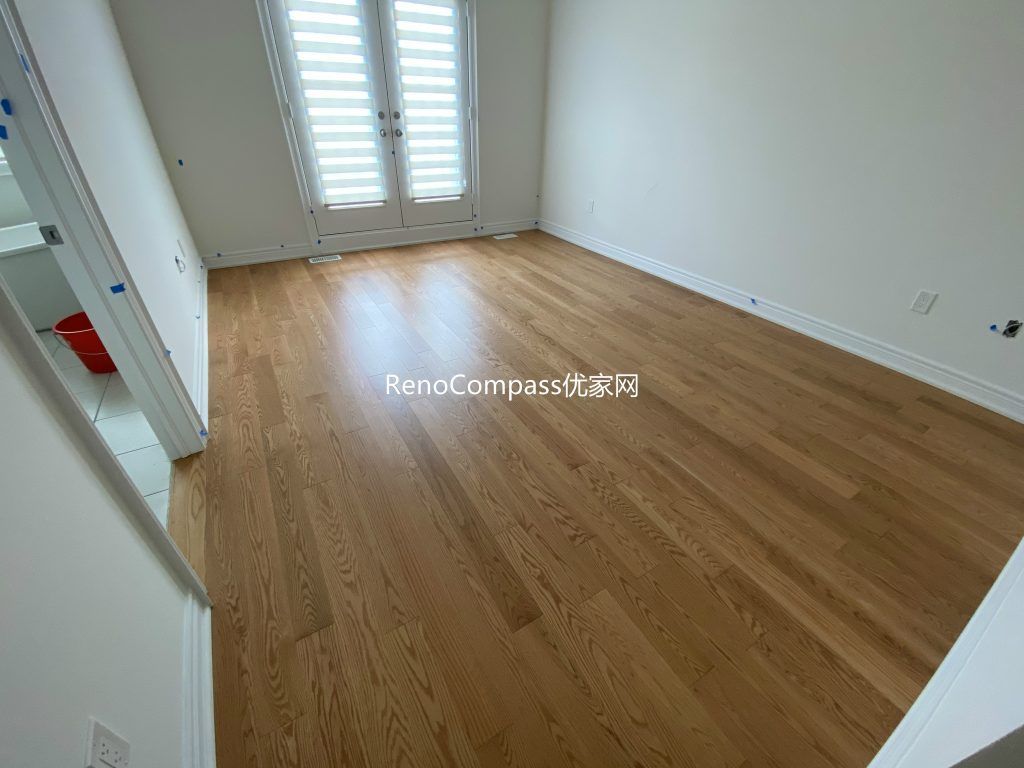 Beautifully renovated bedroom in Richmond Hill with contemporary lighting, neutral tones, and warm laminate flooring by Reno Compass.