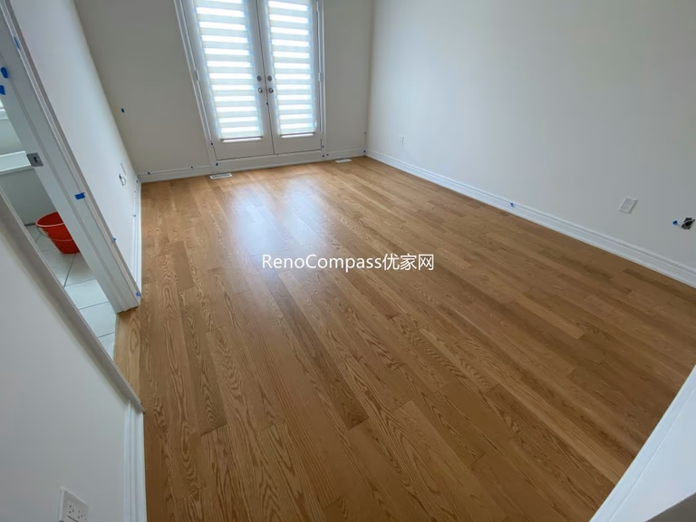 Beautifully renovated bedroom in Richmond Hill with contemporary lighting, neutral tones, and warm laminate flooring by Reno Compass.