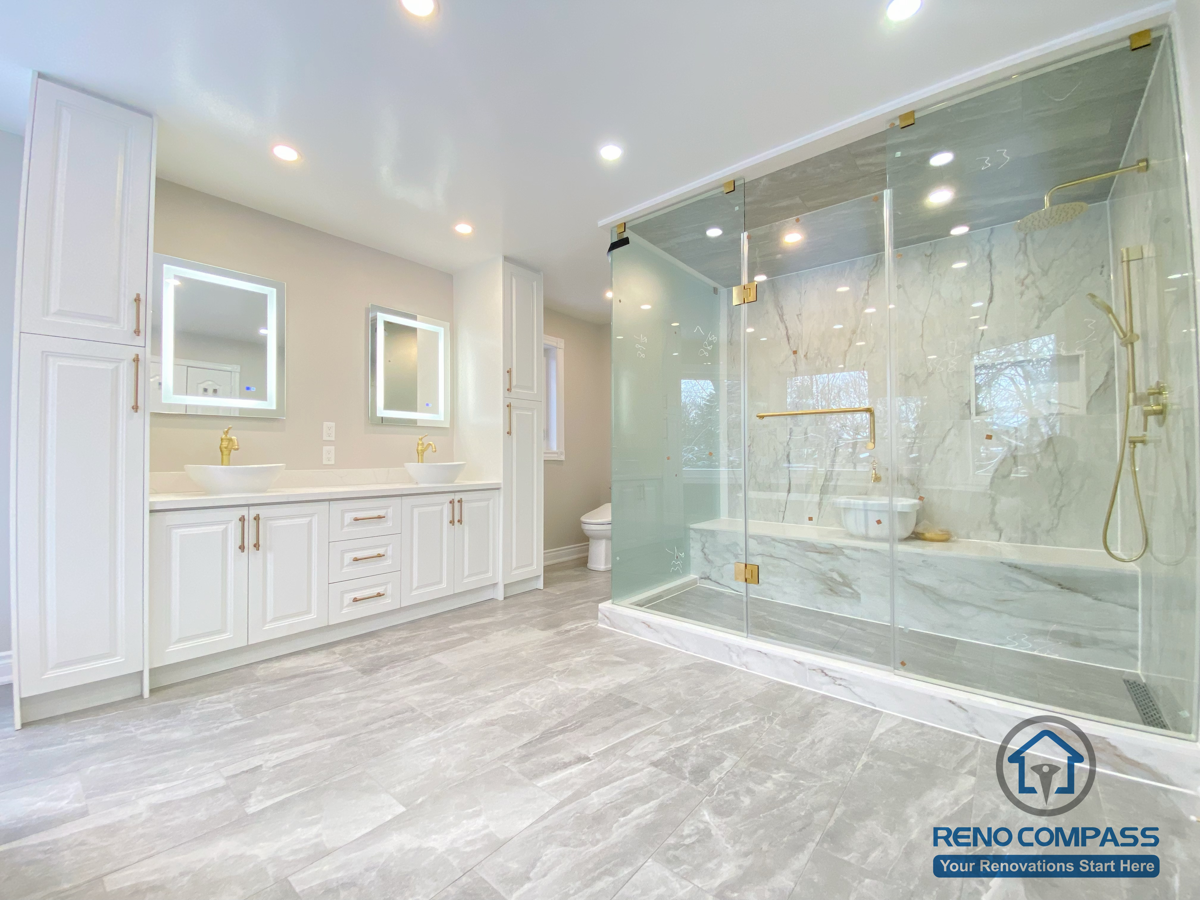 This Richmond Hill bathroom renovation showcases a bright and elegant design featuring a frameless glass shower enclosure, built-in bathtub, marble-style wall tiles, and gold-finish fixtures. The custom white vanity with integrated lighting mirror and large-format floor tiles enhance both functionality and visual openness. This project reflects high-quality craftsmanship and thoughtful layout planning for a modern bathroom renovation in Richmond Hill.