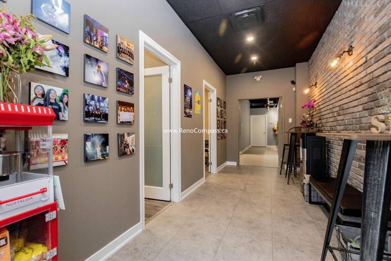 A complete commercial interior renovation in Richmond Hill featuring professional paint finishes, modern glass-panel doors, and a decorative brick feature wall. This project for The Singing School highlights a high-contrast design with a black ceiling and recessed lighting for a modern studio atmosphere.