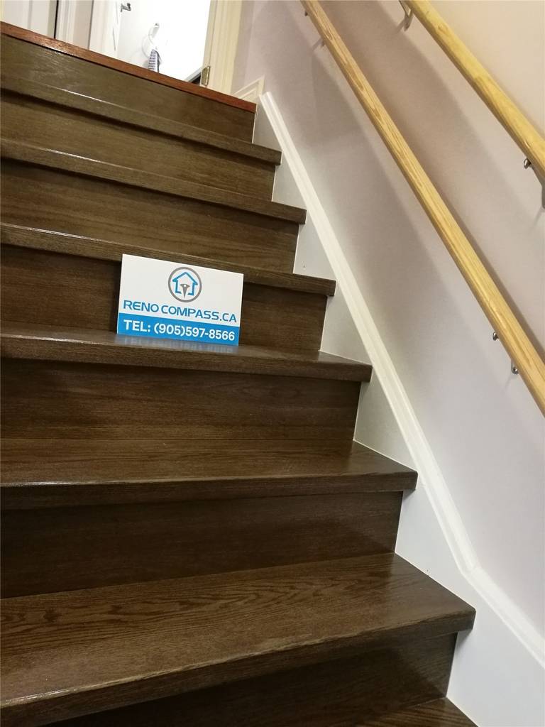 This image features a finished staircase as part of a Markham basement renovation project. The staircase includes dark hardwood stair treads, clean white stringers, and a modern handrail system, creating a safe and visually cohesive transition between floors. The updated staircase design aligns with the basement flooring and overall interior finishes, enhancing both functionality and aesthetics. This upgrade reflects the attention to detail and craftsmanship delivered by a professional Toronto Renovation Company.