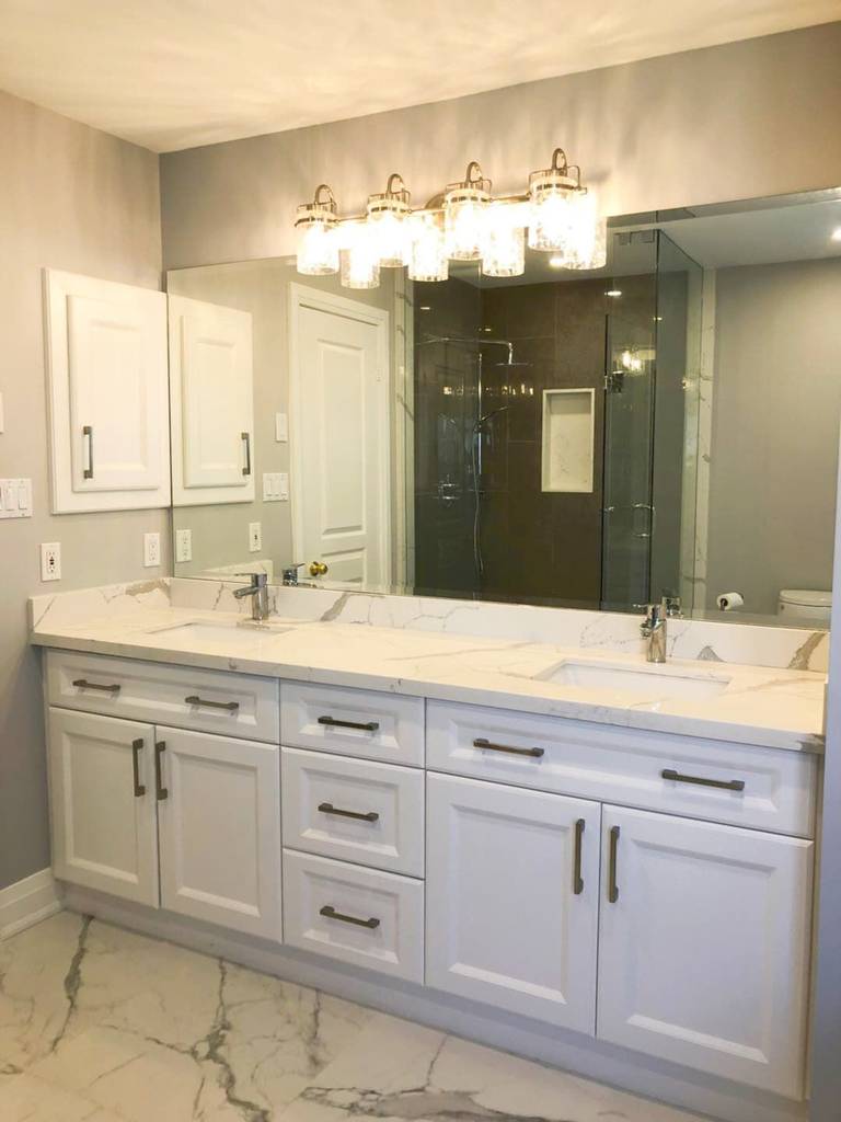 This Richmond Hill bathroom renovation features a modern double-sink vanity with custom white shaker cabinetry, quartz countertops, and sleek black hardware. The upgraded layout improves both storage and daily functionality while maintaining a clean and timeless aesthetic. Large-format marble-style flooring and a glass shower enclosure enhance the luxury feel, creating a bright and elegant space ideal for modern family living. Professionally completed by a trusted Toronto renovation company, this project combines durability, comfort, and refined design for long-term use.