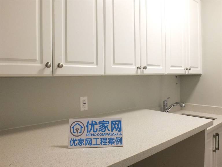 This Richmond Hill basement renovation highlights a detailed view of the utility area, featuring a quartz countertop, custom upper cabinets, and a built-in sink. The clean finishes and practical layout provide efficient storage and workspace, ideal for laundry or additional household use.