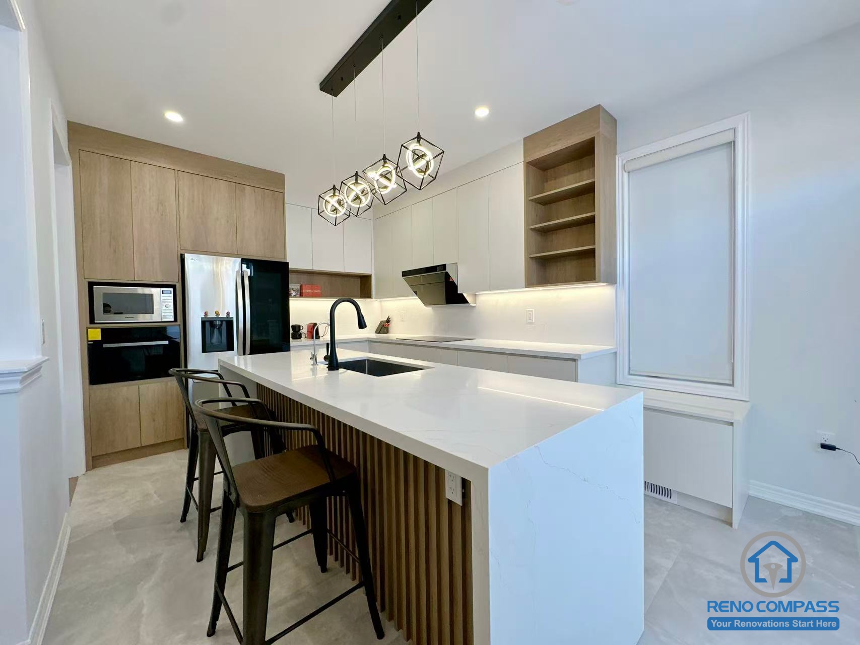 This Stouffville kitchen renovation showcases a contemporary island design featuring vertical wood panel detailing, a quartz countertop, and a matte black sink and faucet. Modern pendant lighting and full-height cabinetry create a bright, open-concept cooking and dining space. Completed by a reliable Toronto renovation company, Reno Compass Inc., this project highlights refined material selection and modern kitchen craftsmanship.