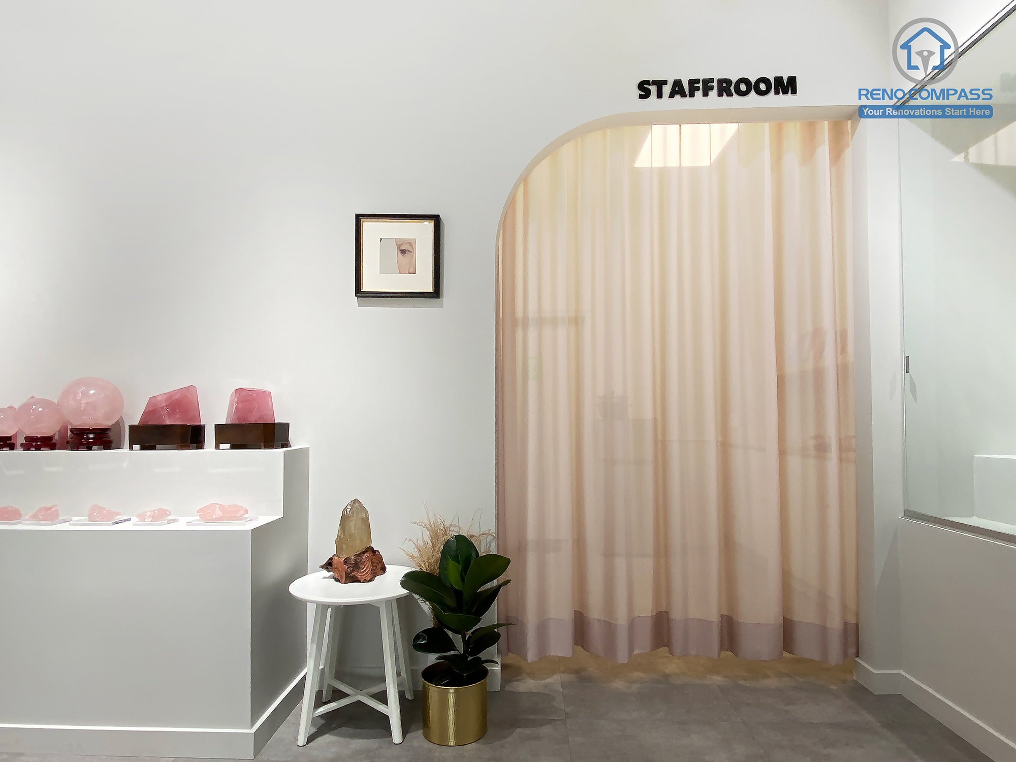 This image showcases a thoughtfully designed staff room entrance within a crystal shop renovation in Markham. A custom curved archway combined with soft sheer curtains creates a gentle transition between public retail space and private staff area. The surrounding crystal displays, minimalist finishes, and polished concrete flooring maintain visual consistency throughout the store. As a Toronto renovation company, Reno Compass designs retail spaces that balance customer-facing aesthetics with functional back-of-house planning.
