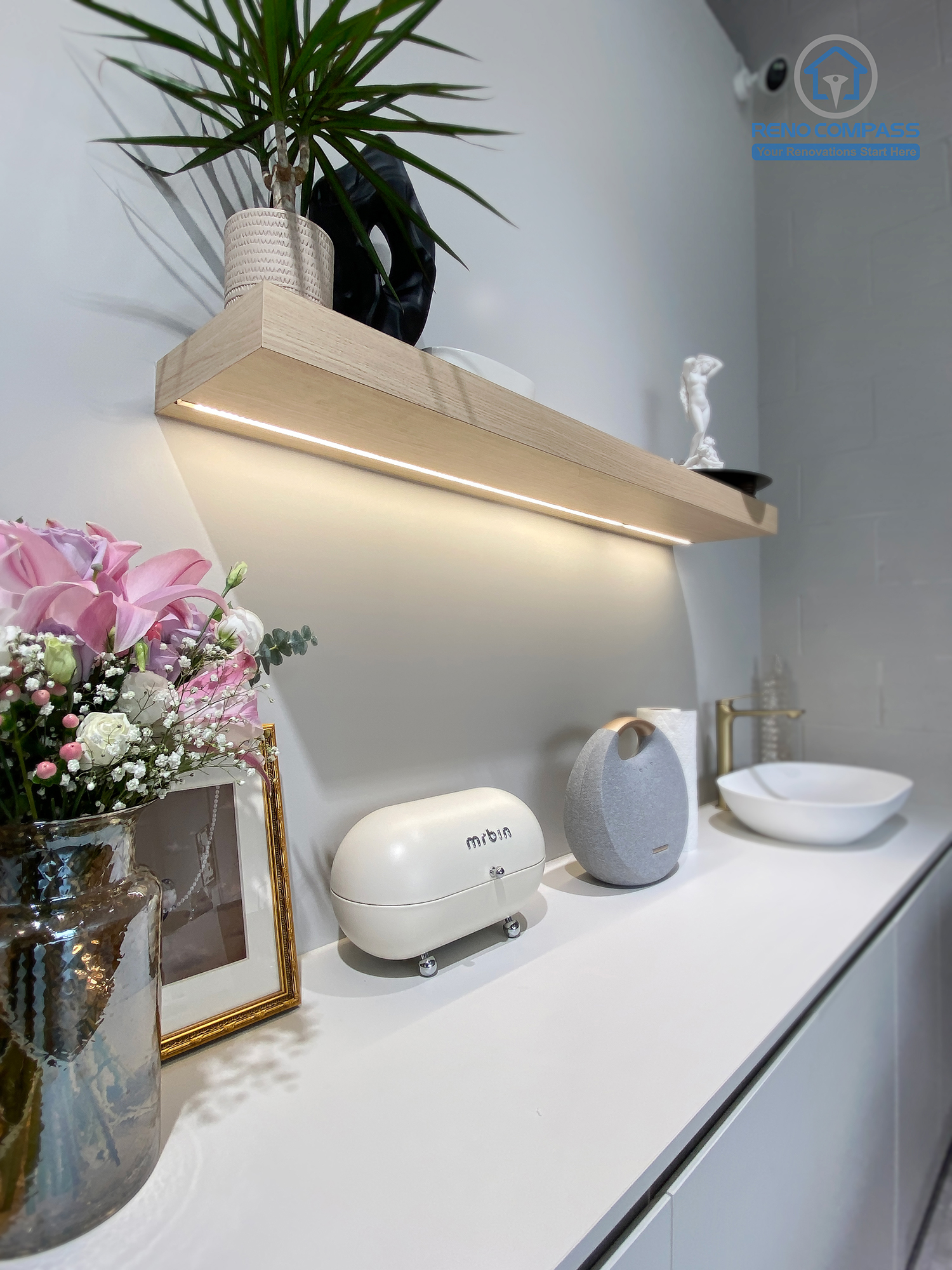 This image features a custom cabinetry and utility counter designed as part of a crystal shop renovation in Markham. The space includes built-in storage cabinets, a minimalist countertop with integrated sink, floating display shelf, and carefully styled decorative elements. Soft neutral finishes and functional layout support daily retail operations while maintaining a calm, curated aesthetic. As a Toronto renovation company, Reno Compass delivers retail renovation solutions that combine practical workspace design with refined visual presentation.