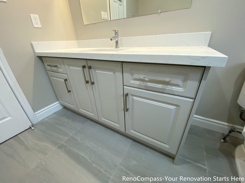 This Mississauga interior renovation highlights a modern bathroom vanity featuring a quartz countertop, soft gray cabinetry, and functional storage drawers. The clean-lined cabinet design improves organization and daily usability, while the durable countertop provides long-lasting performance. Neutral finishes and streamlined hardware create a balanced, timeless vanity solution that integrates seamlessly into the overall bathroom renovation.