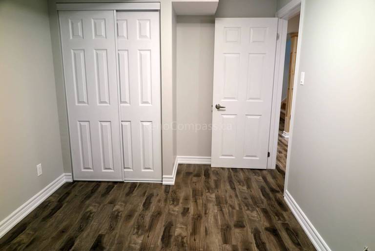 Newly finished Richmond Hill basement highlighting white modern double doors, sleek trim detailing, and premium flooring for a bright and elegant finish.